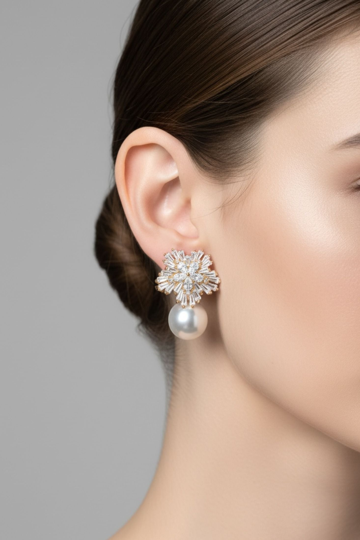 Close-up of a woman wearing a pearl earring with a gray background