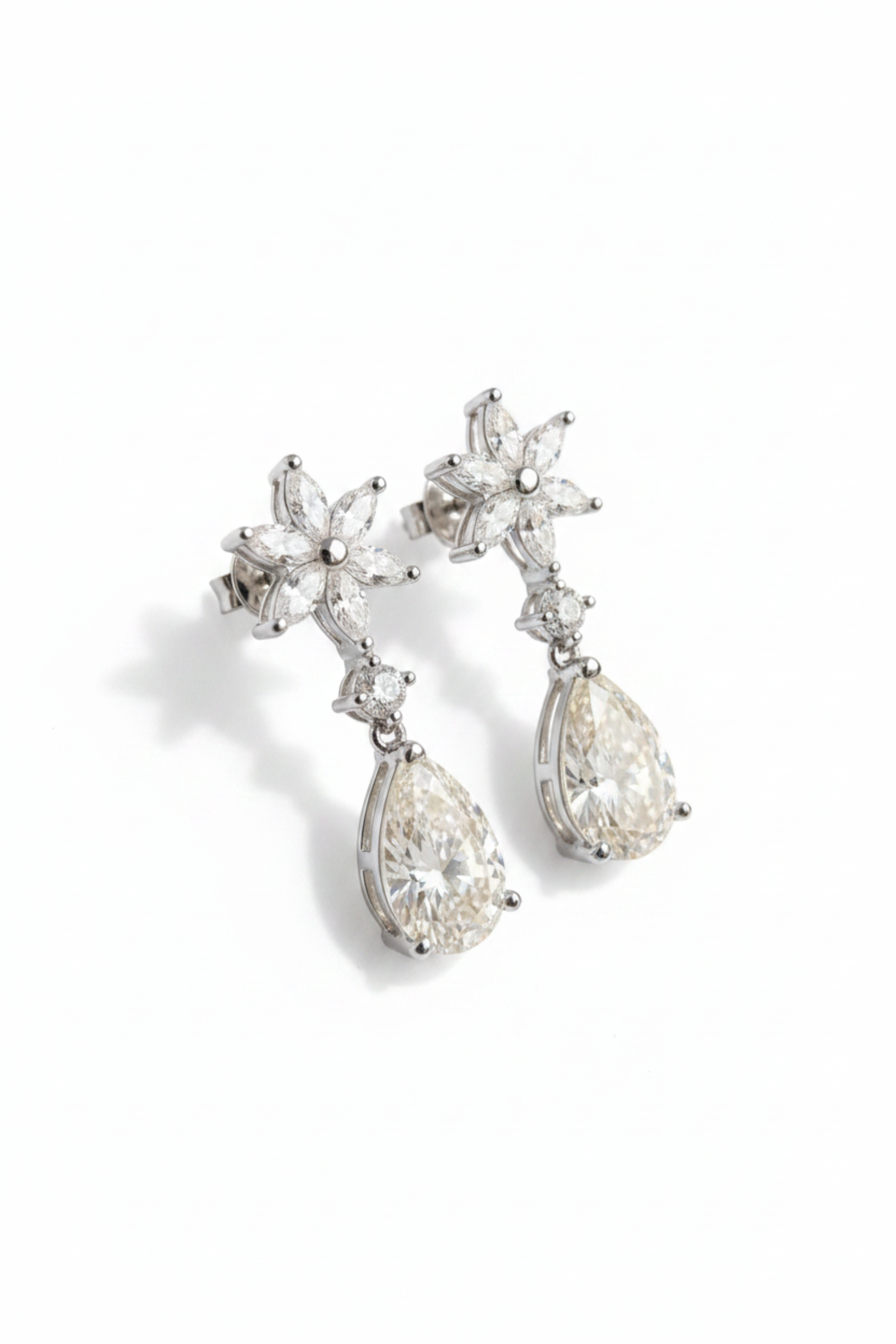A pair of silver-toned drop earrings featuring a floral starburst stud design and pear-cut clear gemstones, shown on a clean white background.