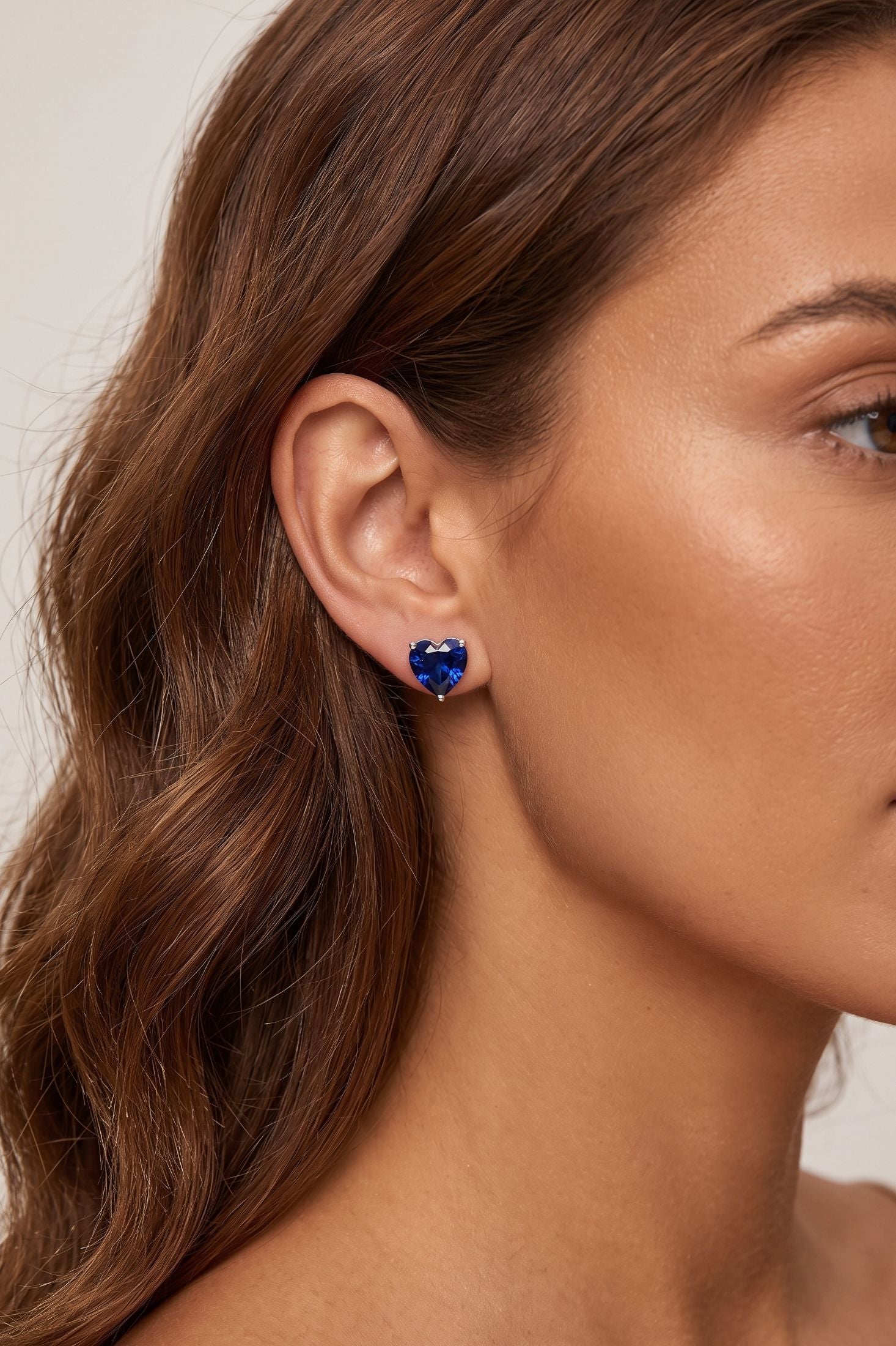 Angled view of Amore Heart Sapphire Stud Earrings Silver, showing heart design, sapphire detailing, silver finish and the jewellery profile.