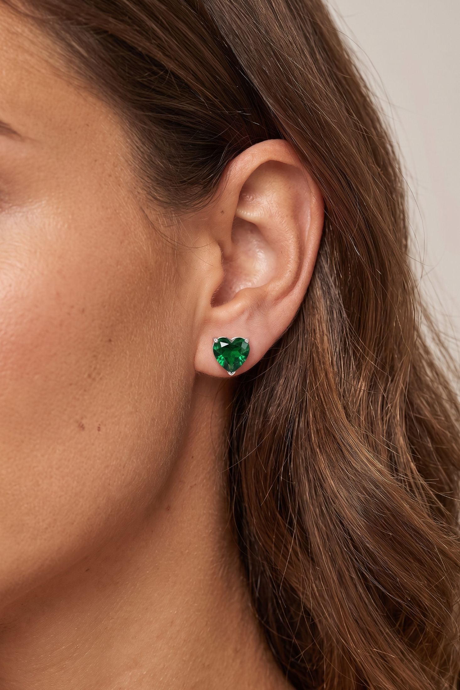Angled view of Amore Heart Emerald Stud Earrings Silver, showing heart design, emerald detailing, silver finish and the jewellery profile.