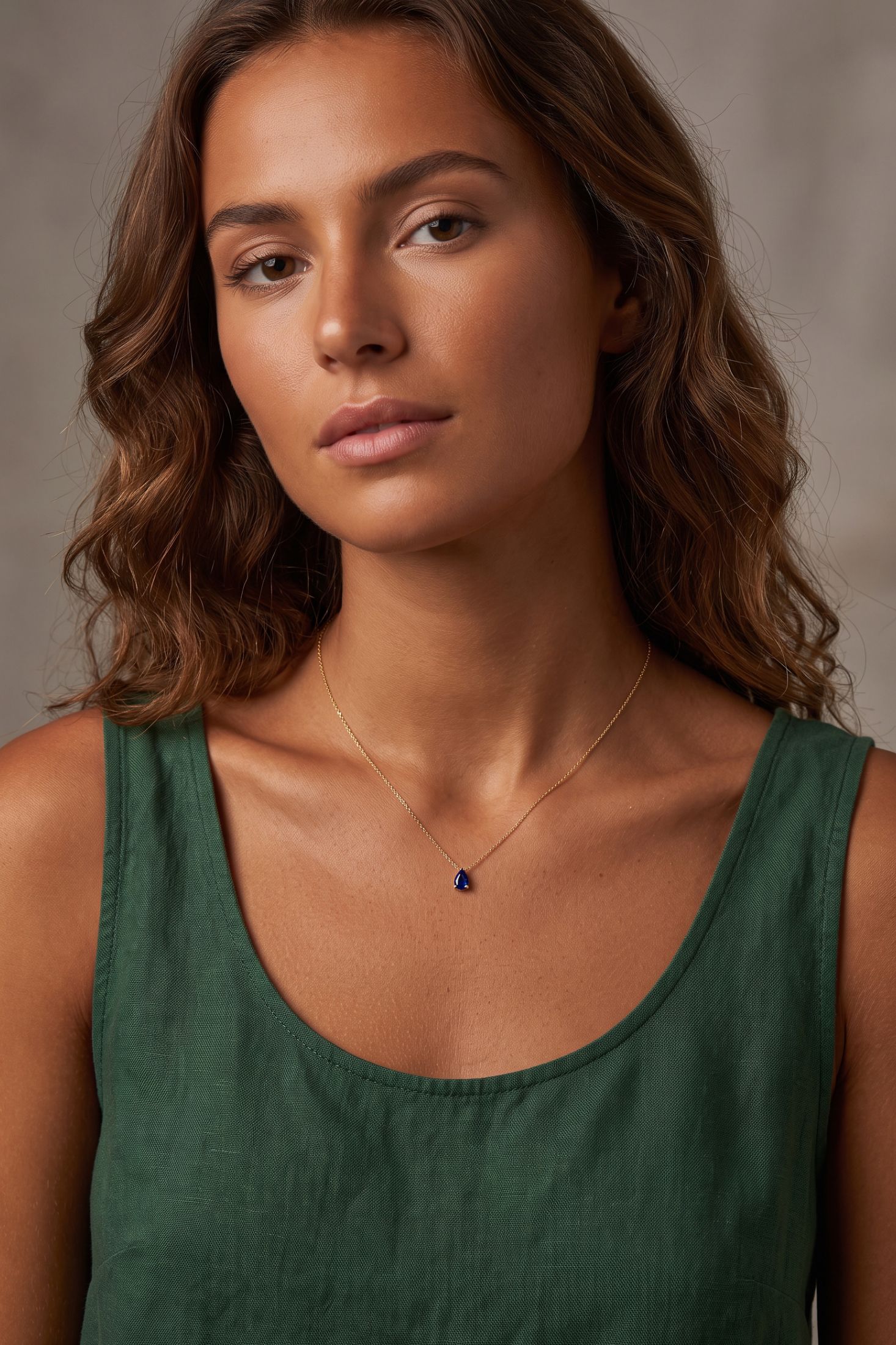 Angled view of Adele Teardrop Necklace Gold Sapphire, showing sapphire detailing, gold finish and the jewellery profile.
