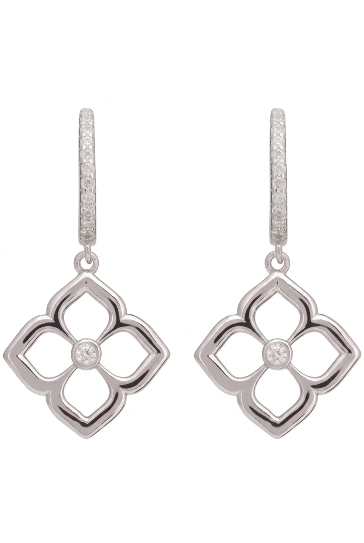 A pair of silver-toned dangle earrings with a four-petal clover motif and a small clear stone in the center, featuring a pavé-set top bar, on a plain white background.
