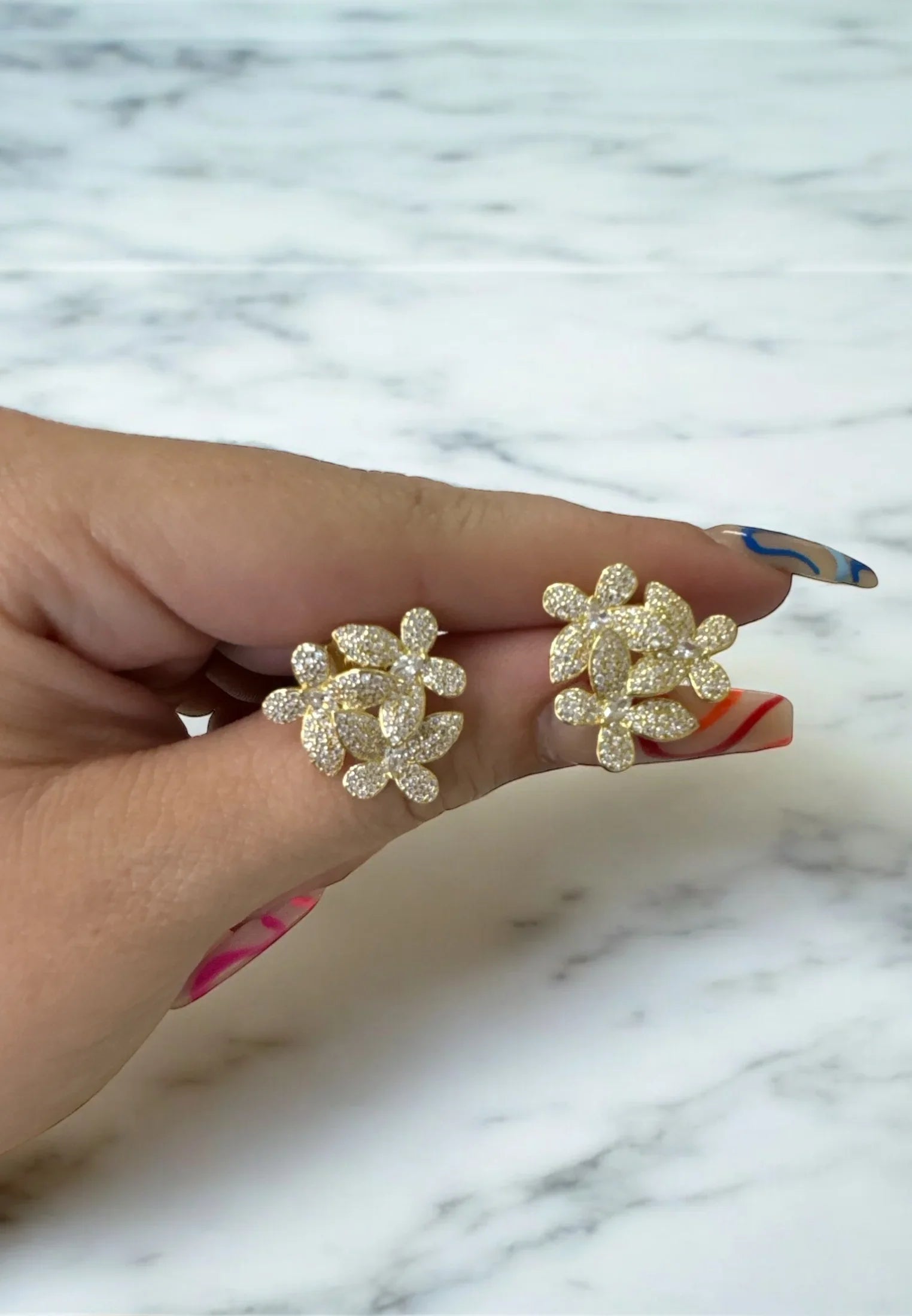 The earrings held up by a hand model.