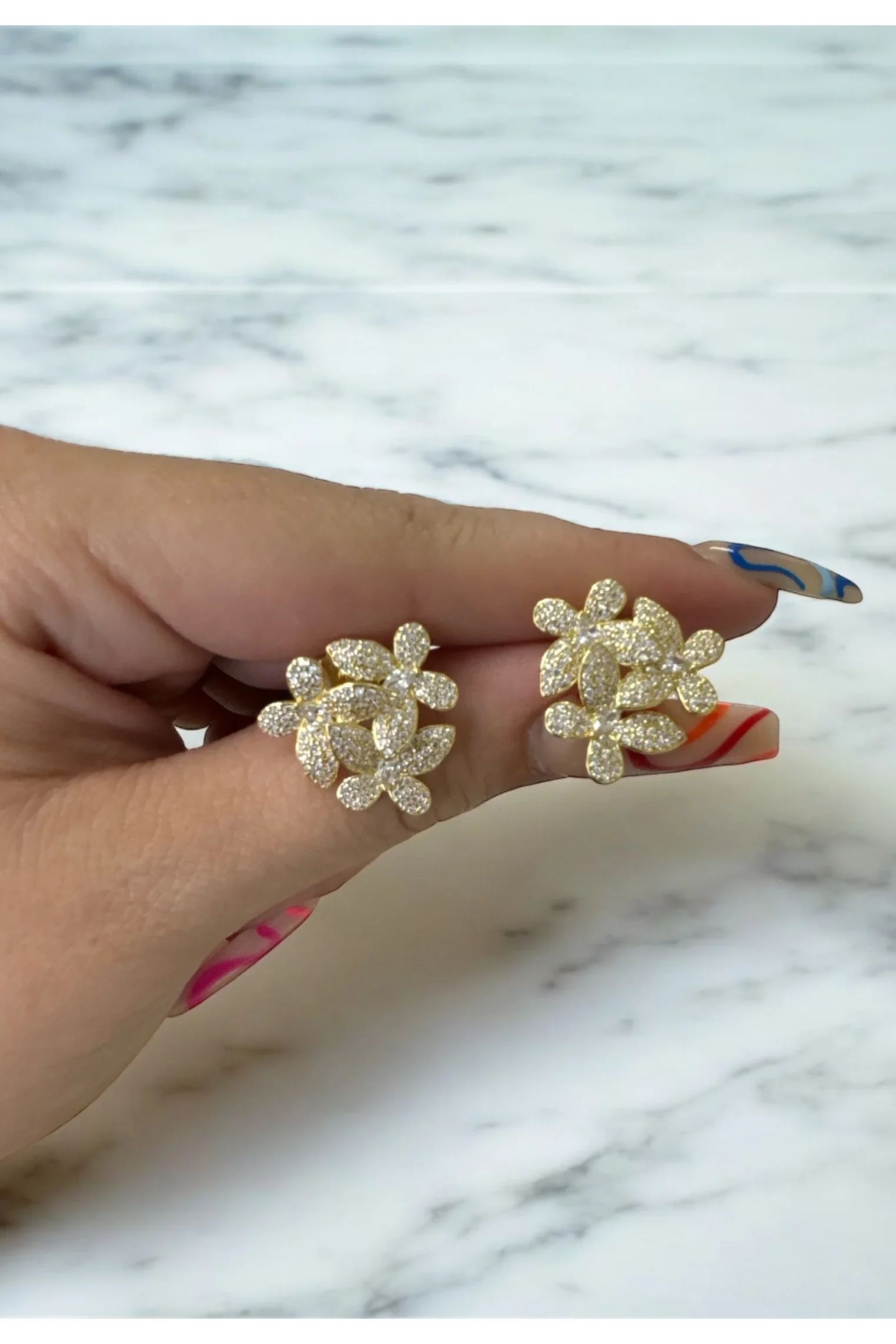 The earrings held up by a hand model.