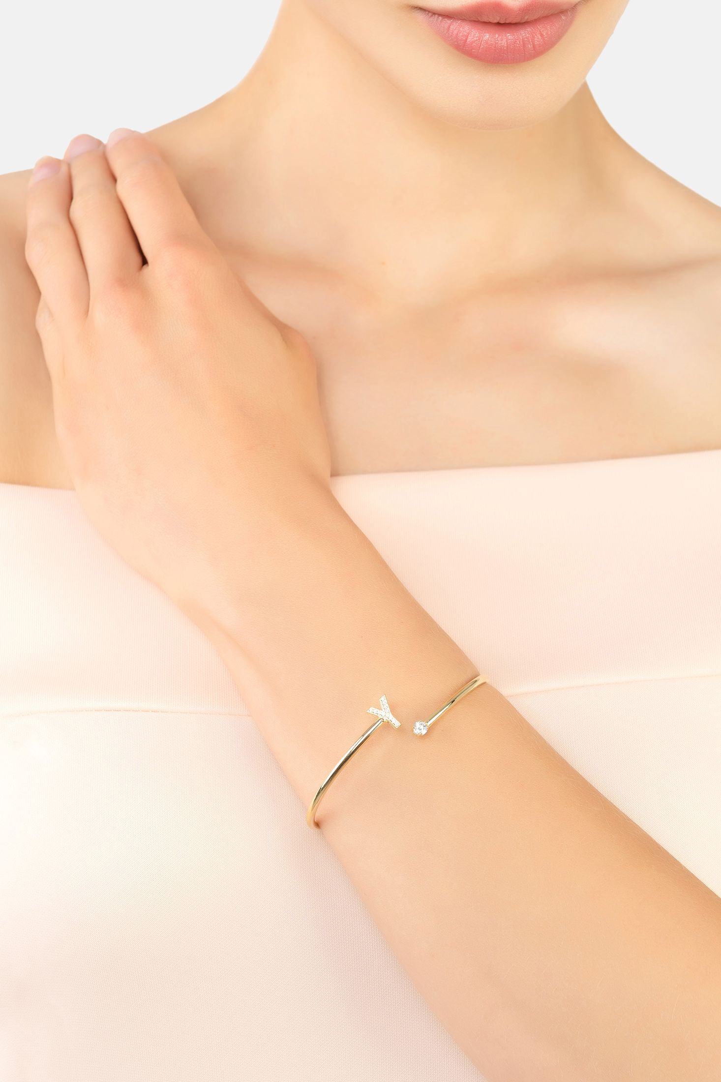 A bangle in the shape of a letter Y on a person's wrist with a plain background