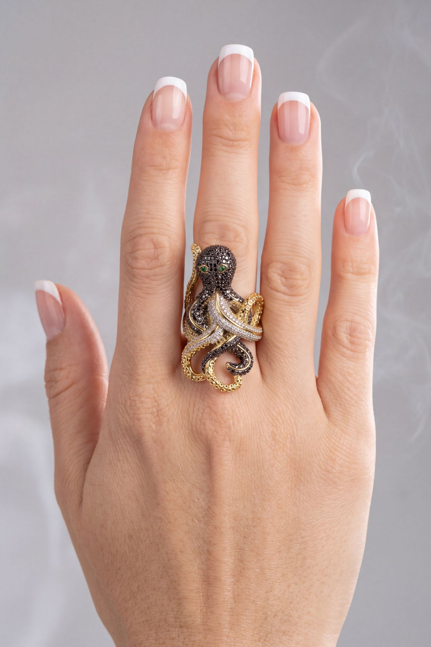 Octopus statement ring with black and white pavé diamonds, green gem eyes, gold tentacles on woman's hand