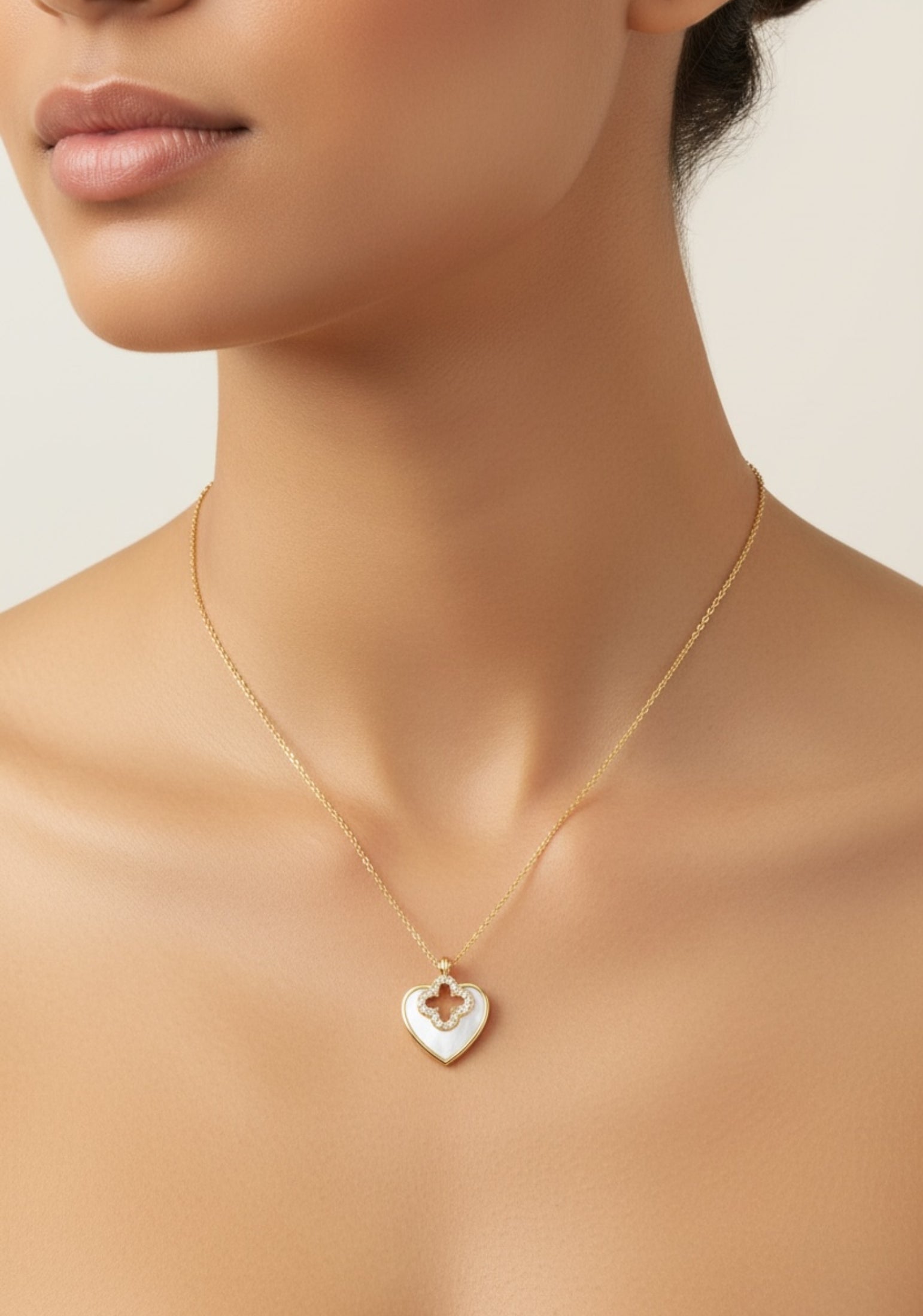 Gold necklace with a heart-shaped pendant on a neutral background