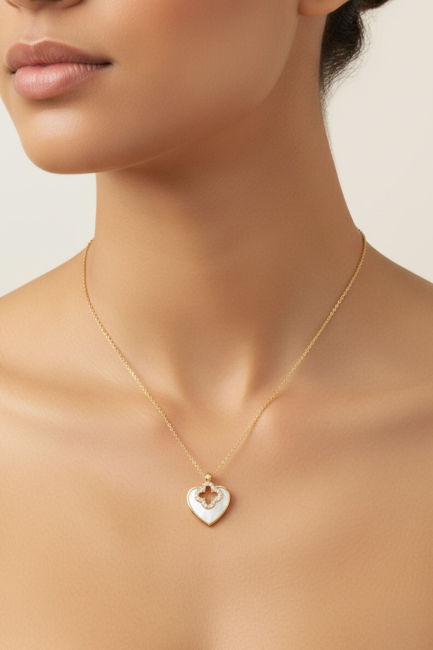 Gold necklace with a heart-shaped pendant on a neutral background