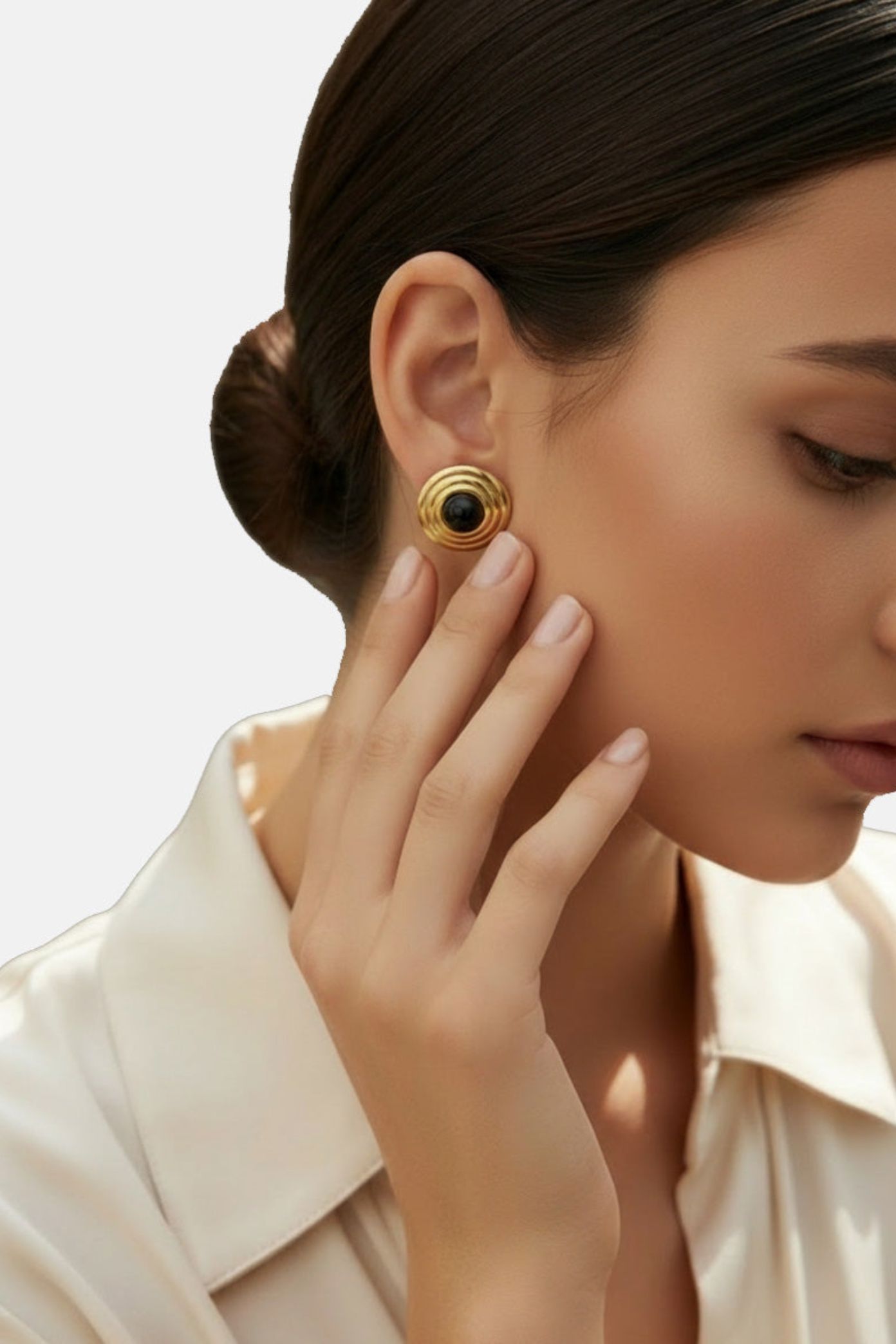 Close-up of a woman wearing gold earrings with a black gemstone on a neutral background