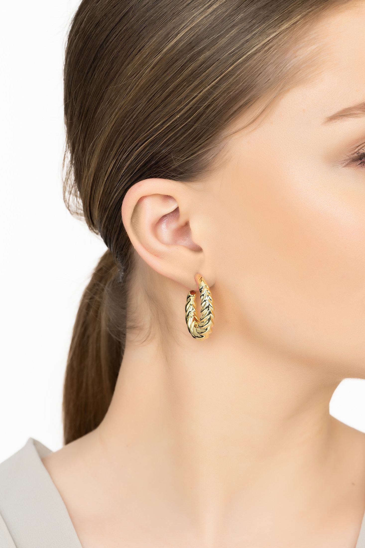 Angled view of Twirl Harmony Hoop Earrings Gold, showing gold finish and the jewellery profile.