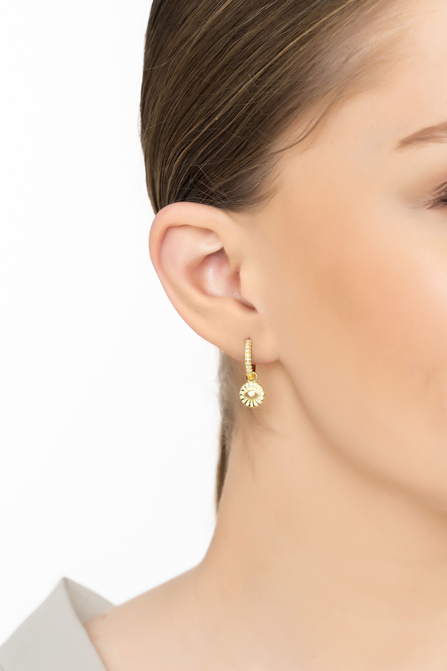Angled view of Illuminati Evil Eye Huggie Hoop Earrings Gold, showing evil eye design, gold finish and the jewellery profile.
