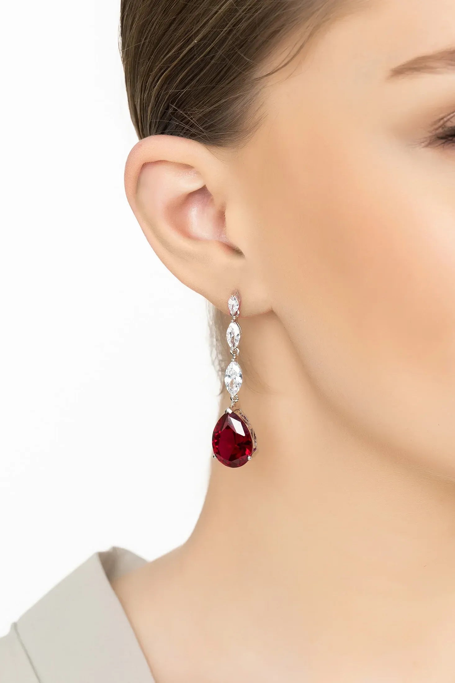 Angled view of Zara Teardrop Ruby Gemstone Earrings Silver, showing ruby detailing, silver finish and the jewellery profile.