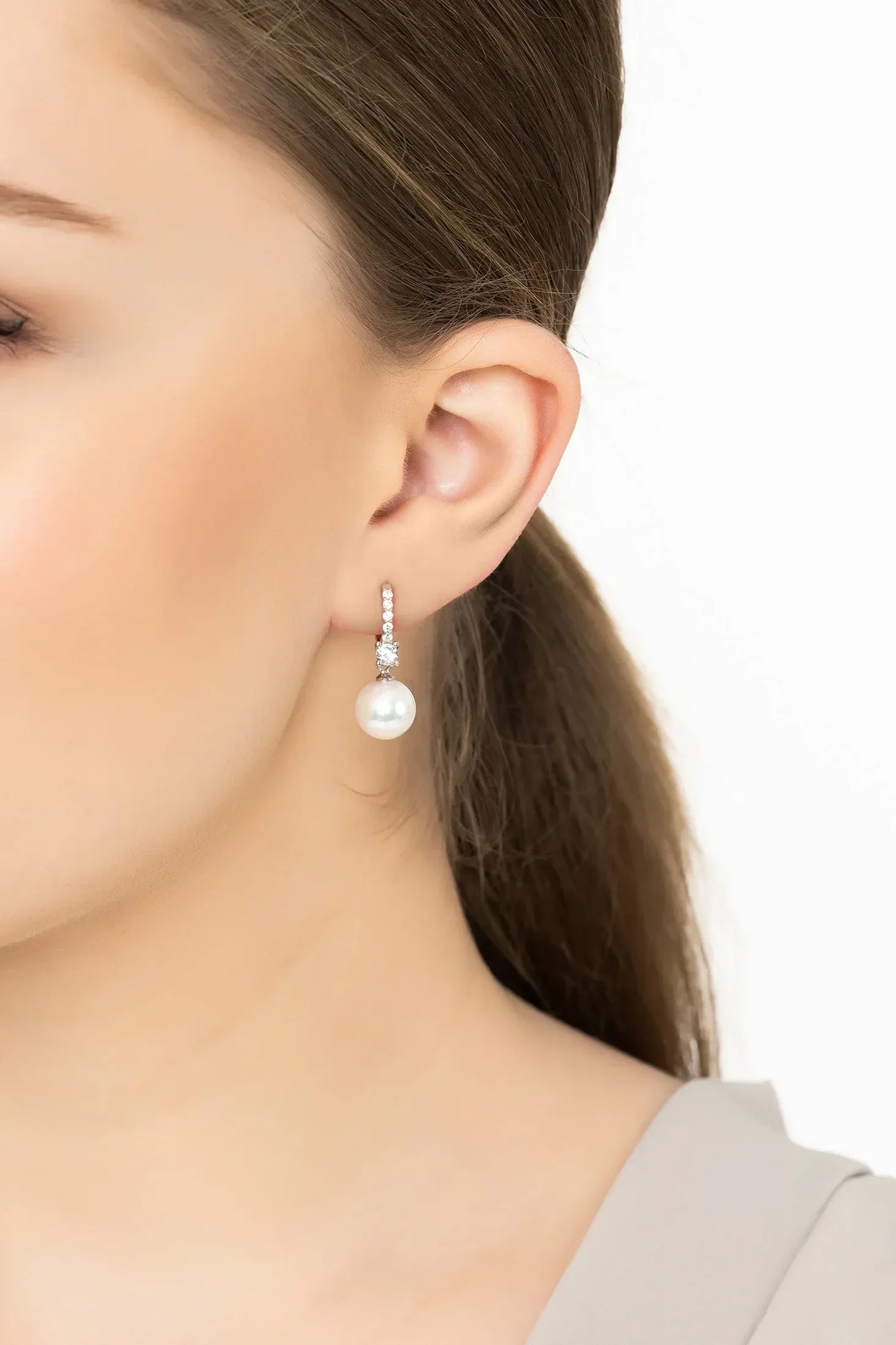 Close-up of a woman wearing pearl earrings with a white background
