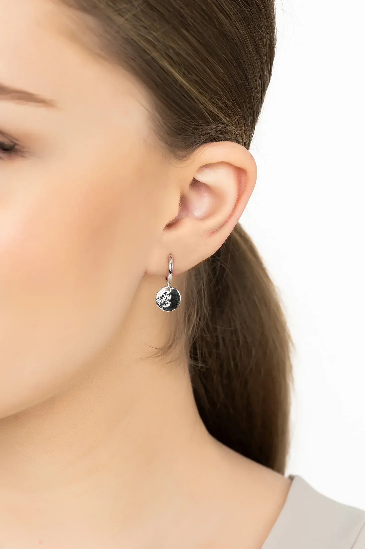 Angled view of Lunar Moon Huggie Hoop Earrings Silver, showing moon design, silver finish and the jewellery profile.