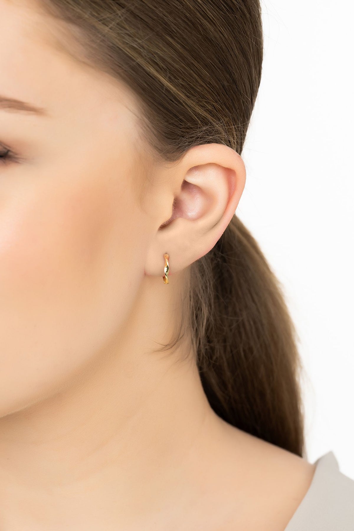 Angled view of Ripple Mini Hoop Earrings Gold, showing gold finish and the jewellery profile.