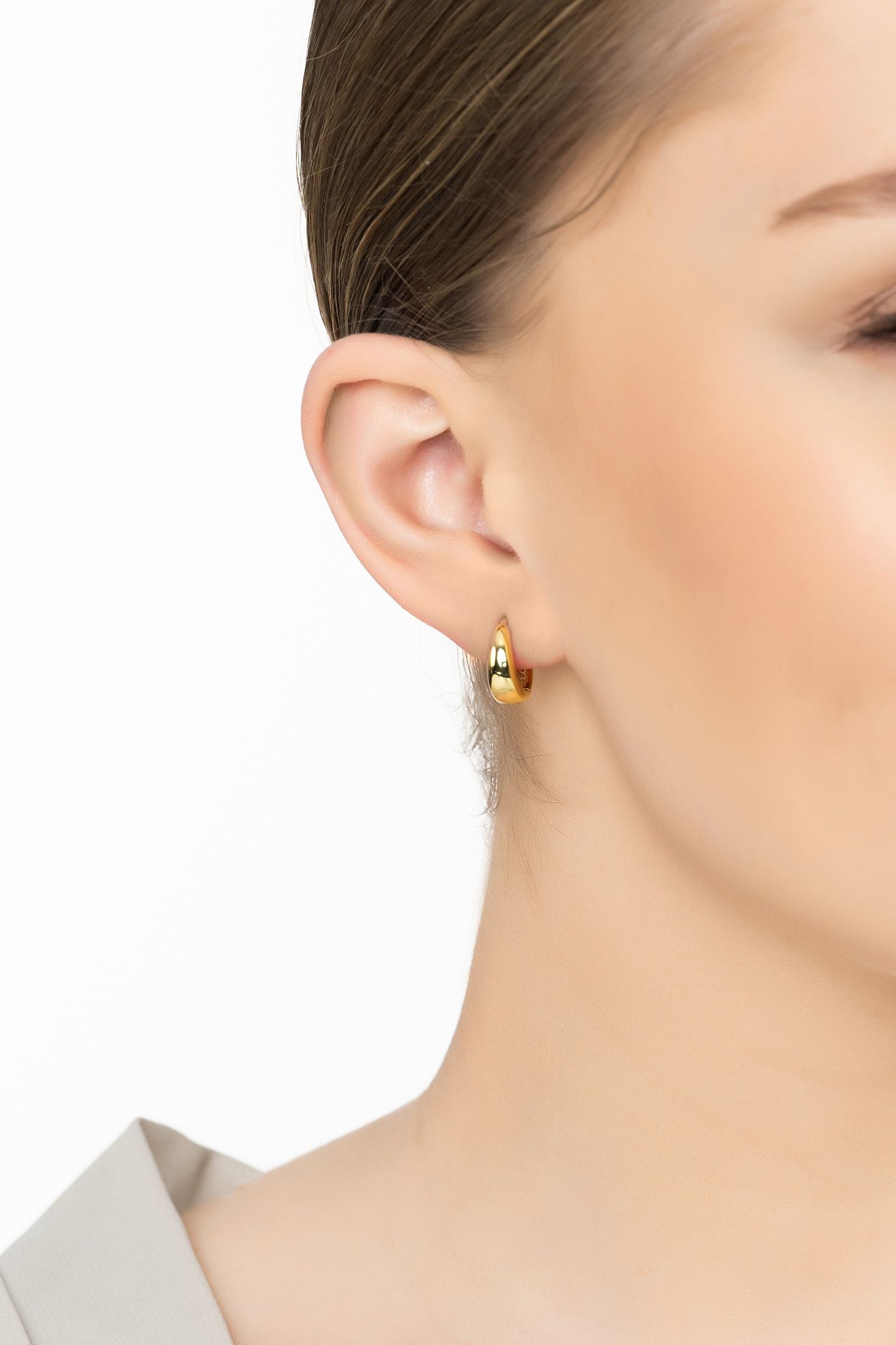 Angled view of Mini Hooplet Earrings Gold, showing gold finish and the jewellery profile.