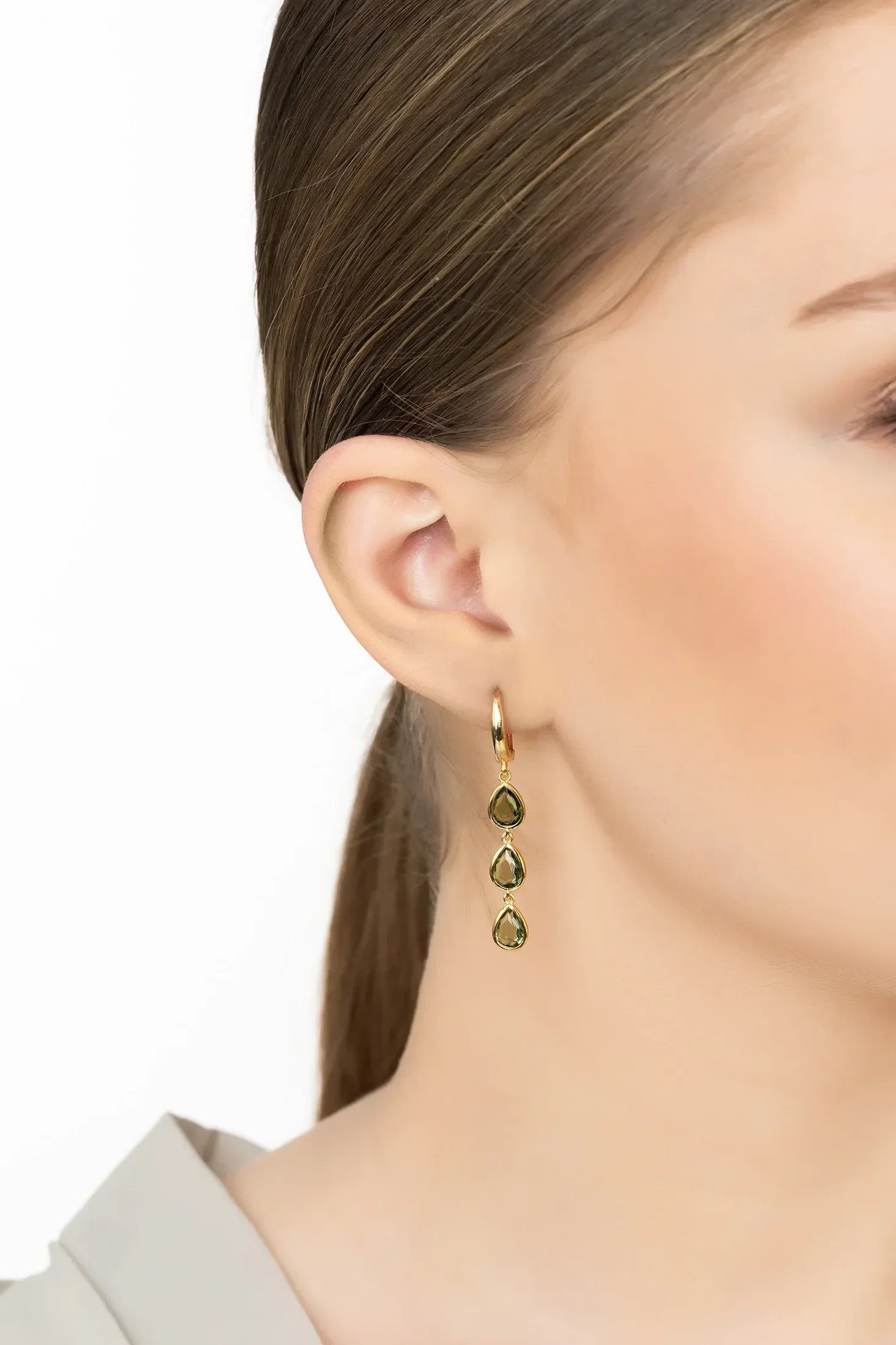 Angled view of Sardinia Triple Teardrop Earrings Gold Peridot, showing peridot detailing, gold finish and the jewellery profile.