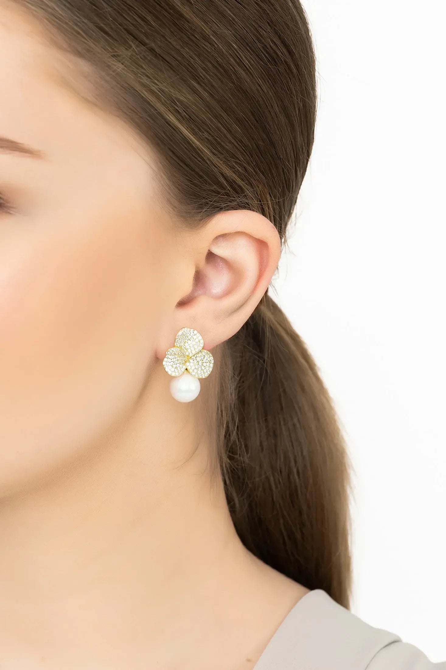 Angled view of Iris Flower And Pearl Dangle Earrings Gold, showing flower design, pearl detailing, gold finish and the jewellery profile.
