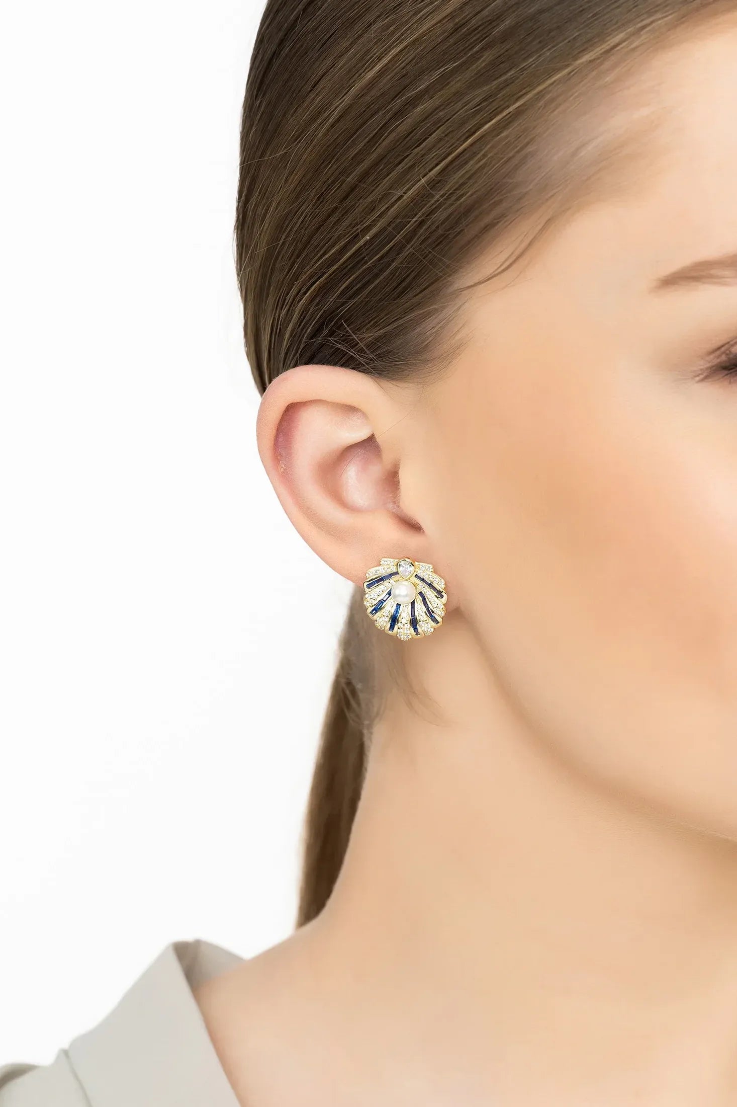 Angled view of Art Deco Scallop Shell Earrings Sapphire Blue With Pearl Gold, showing shell design, pearl and sapphire detailing, gold finish and the jewellery profile.