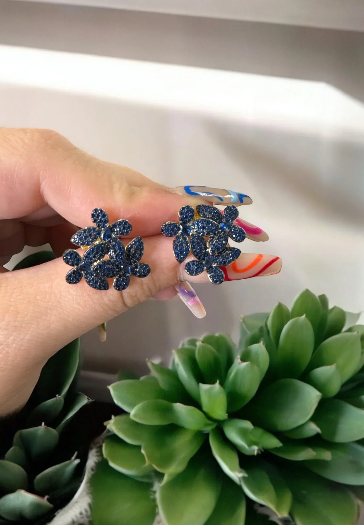 The earrings held up by a hand model.