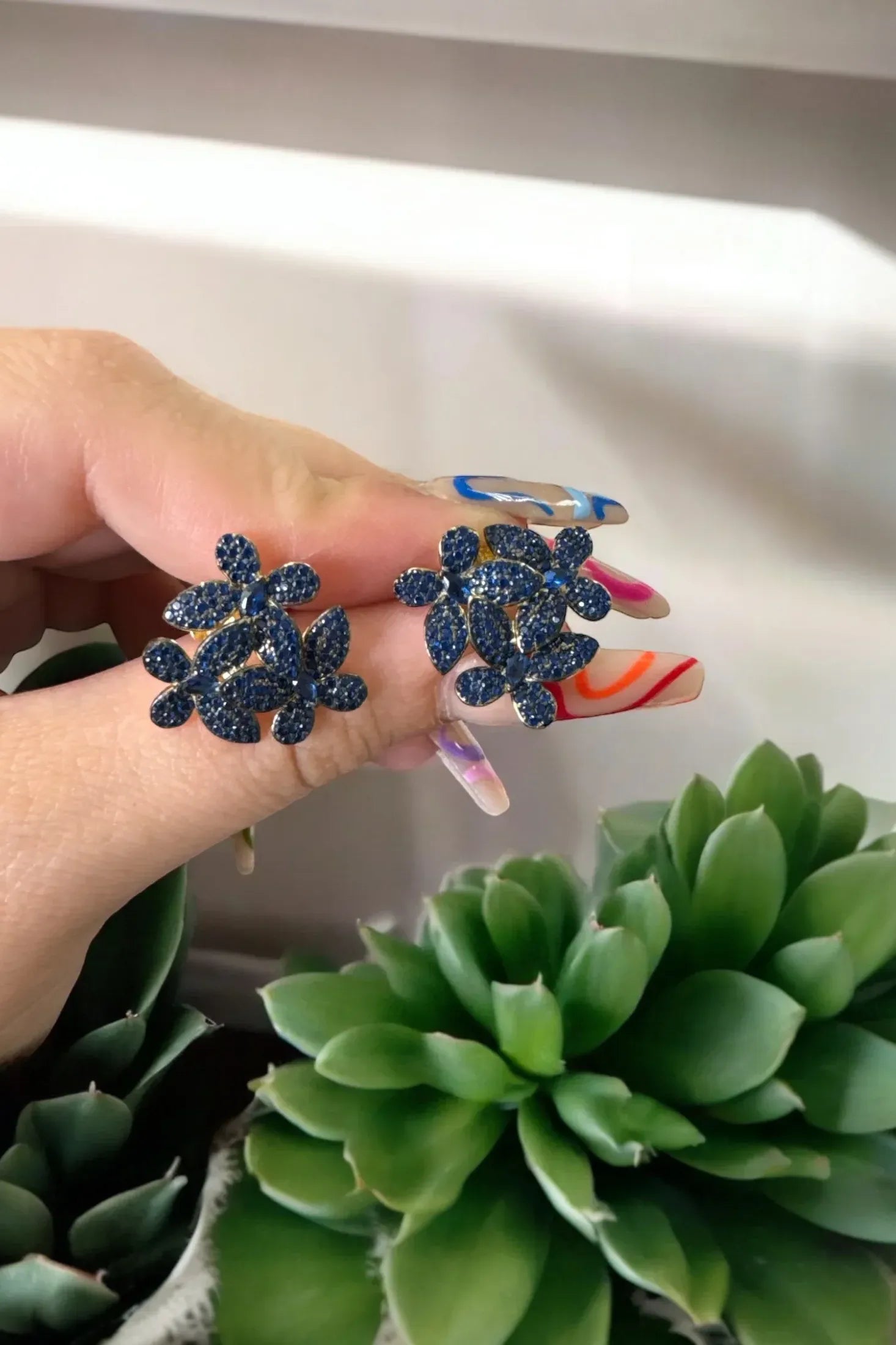 The earrings held up by a hand model.