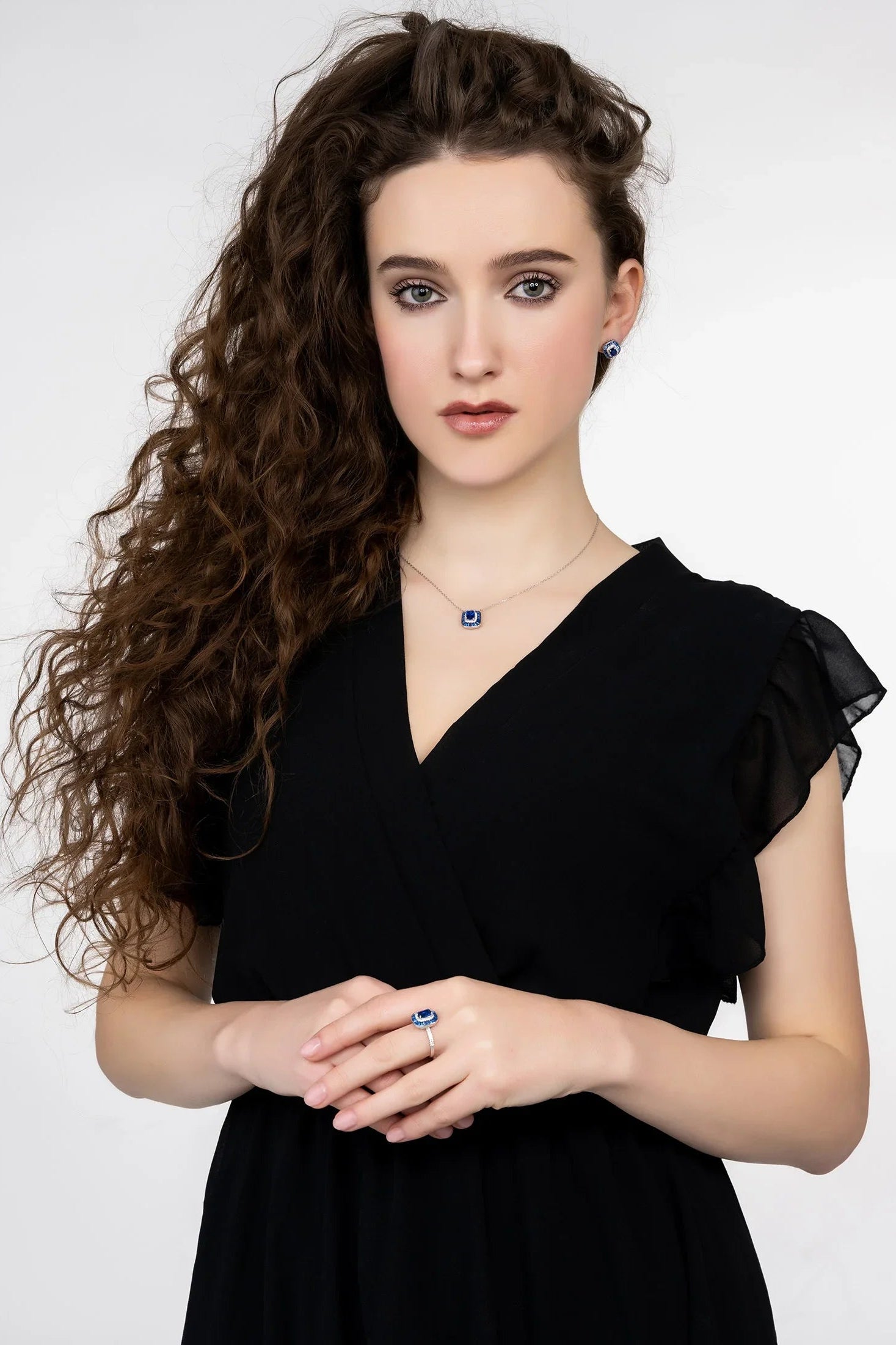 Woman wearing a black dress with ruffled sleeves against a white background