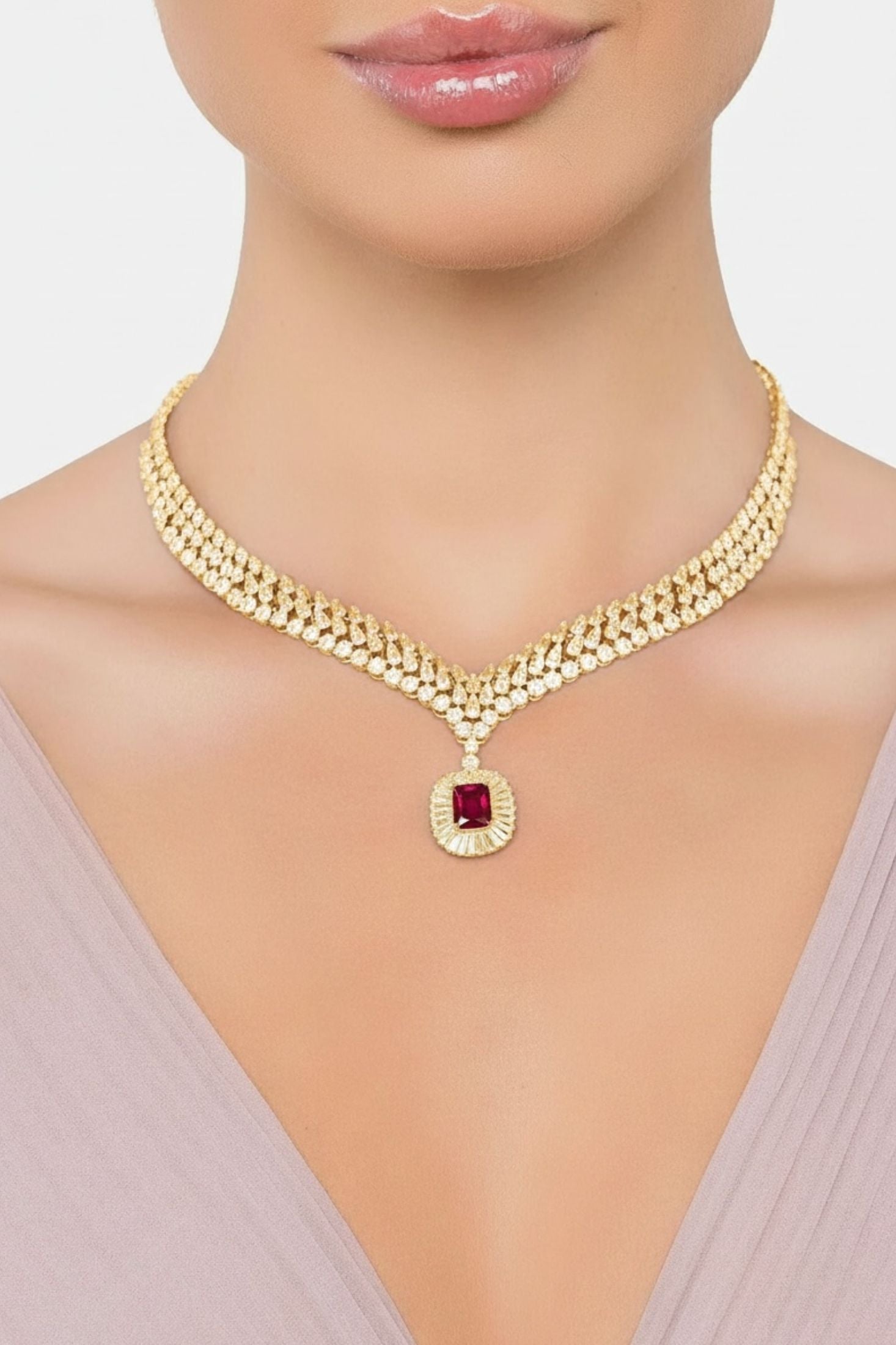 Gold necklace with a red gemstone on a model against a neutral background