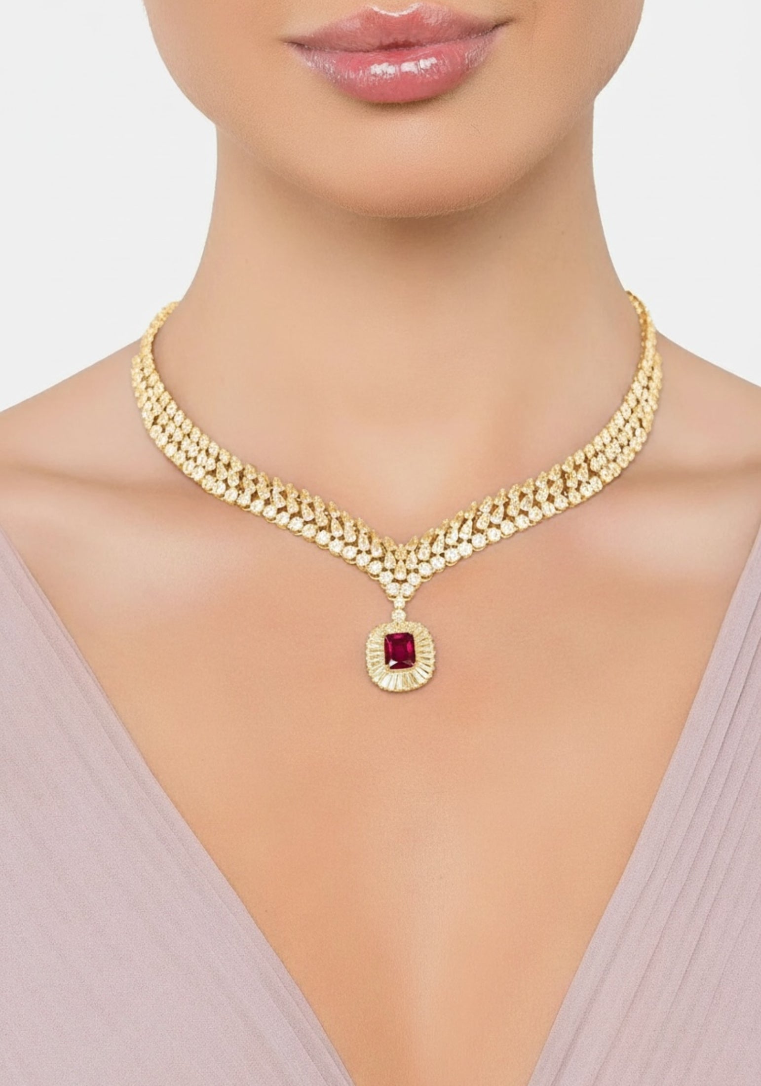 Gold necklace with a red gemstone on a model against a neutral background