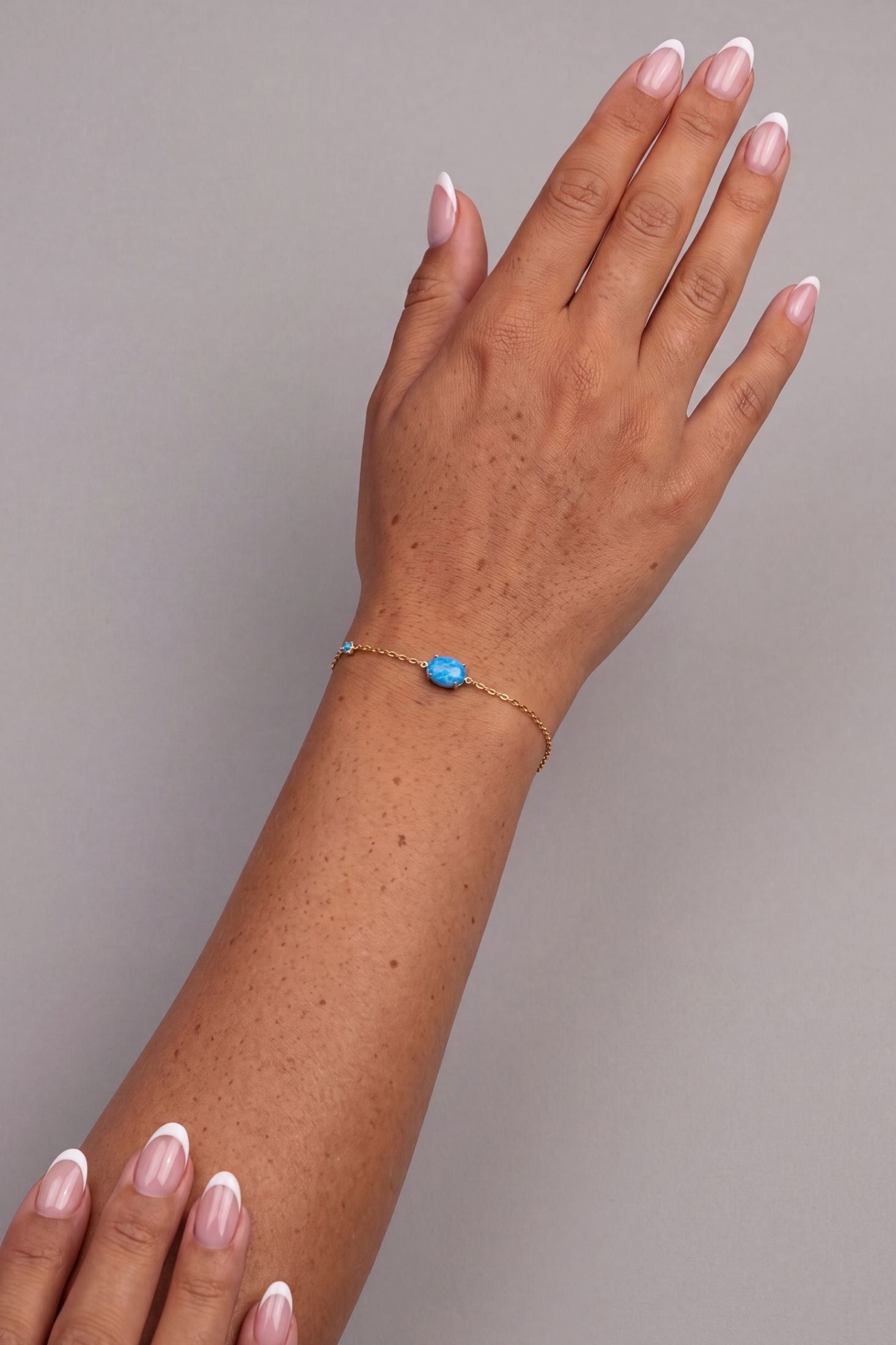 Angled view of Oval Blue Opal Bracelet Gold, showing gold finish and the jewellery profile.