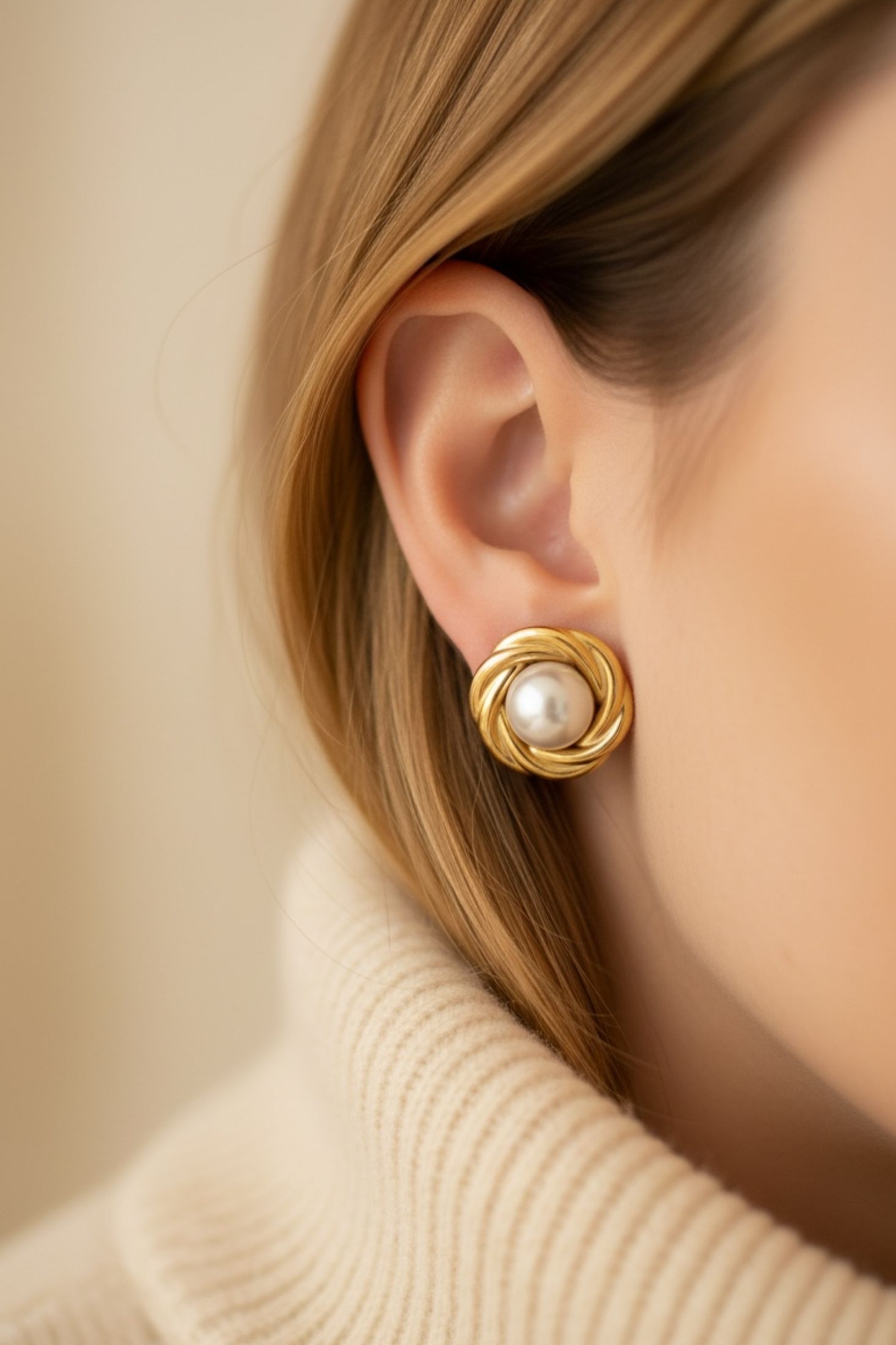 Gold stud earrings with a pearl in the centre worn by a model.