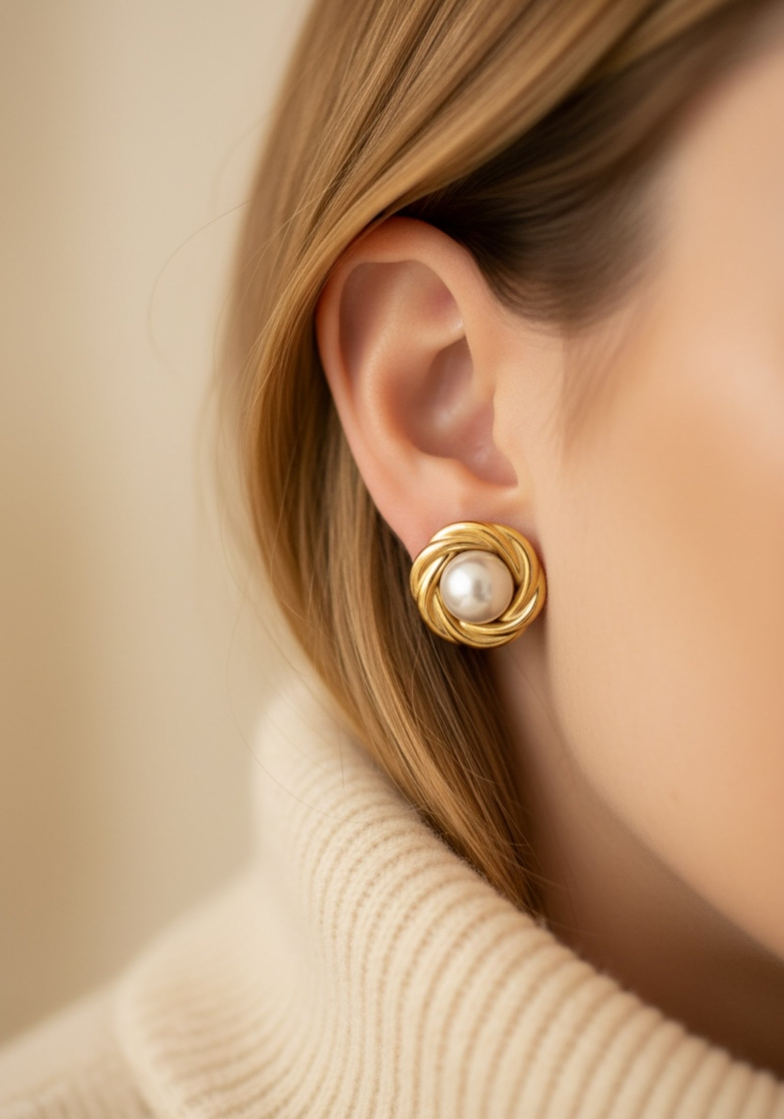 Gold stud earrings with a pearl in the centre worn by a model.