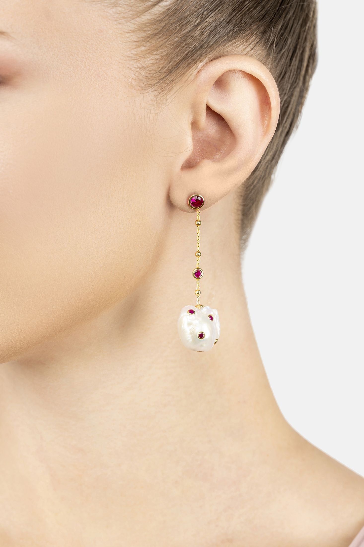 Angled view of Polka Dot Baroque Pearl Chain Drop Earrings Gold Ruby, showing baroque pearl and pearl detailing, gold finish and the jewellery profile.