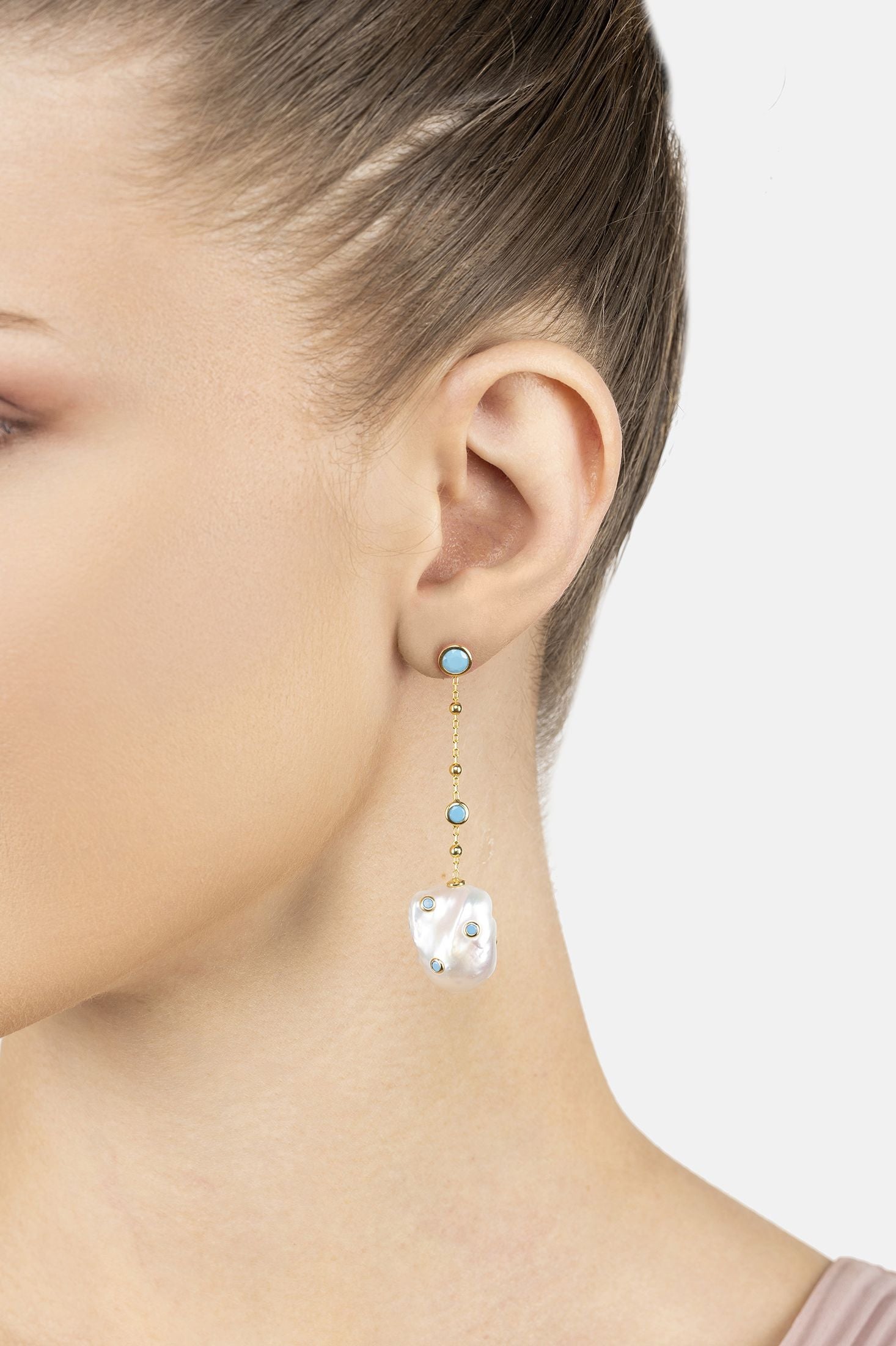 Angled view of Polka Dot Baroque Pearl Chain Drop Earrings Gold Turquoise, showing baroque pearl and pearl detailing, gold finish and the jewellery profile.