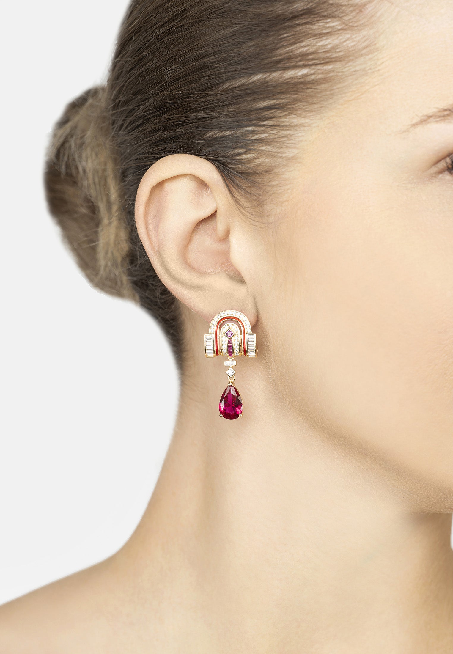 Earring with a red gemstone and white stone on a model's ear against a neutral background