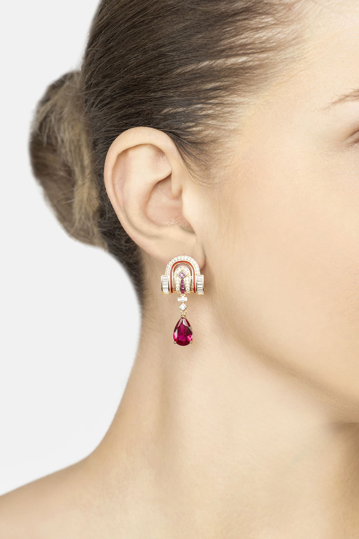 Earring with a red gemstone and white stone on a model's ear against a neutral background