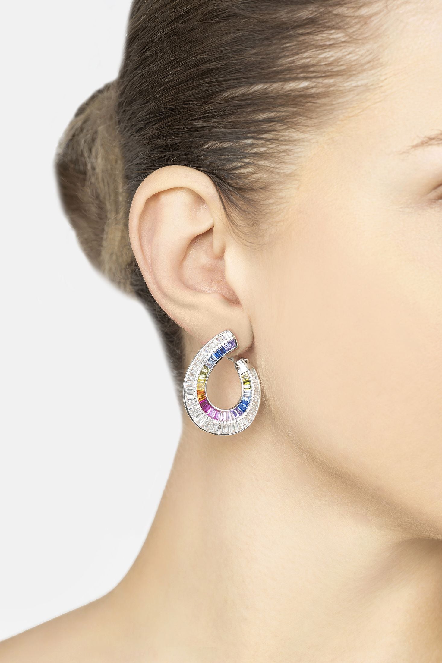 Multicolored hoop earring worn by a person on a light gray background
