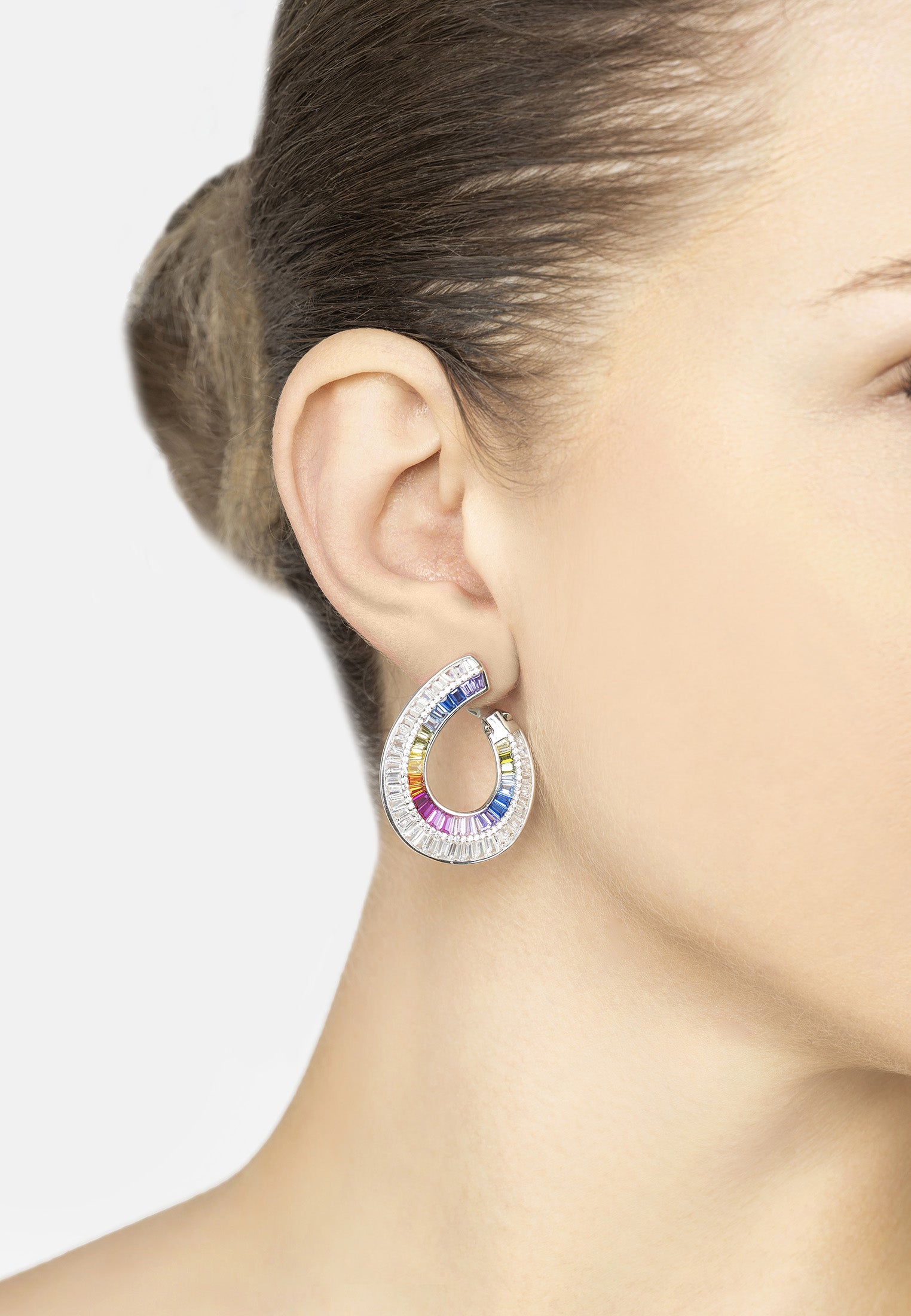 Multicolored hoop earring worn by a person on a light gray background