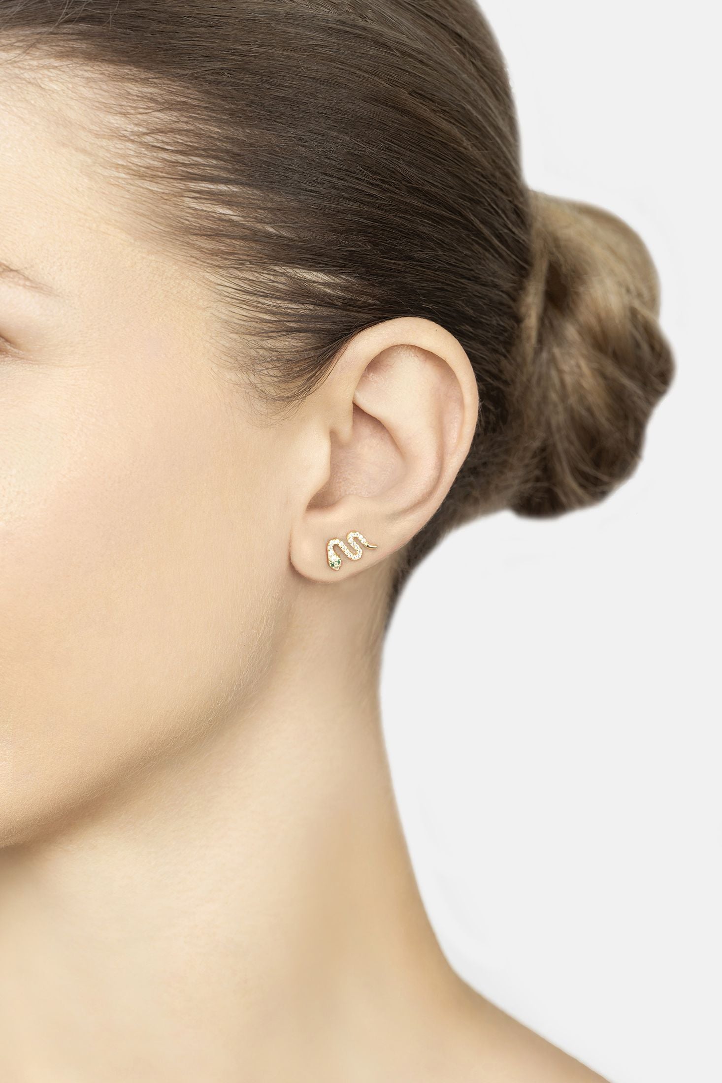 Close-up of a person wearing gold earrings with a minimal background