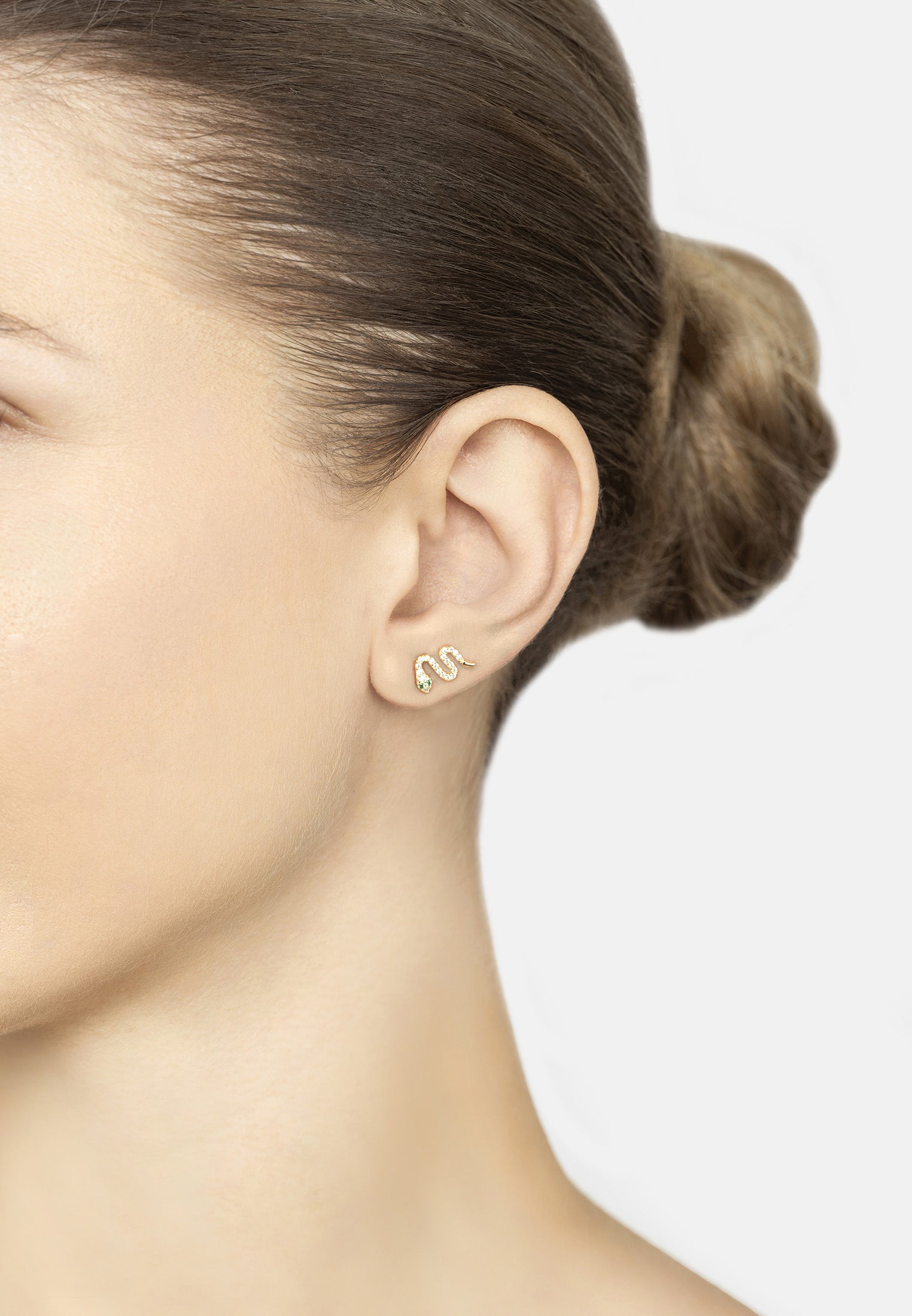 Close-up of a person wearing gold earrings with a minimal background