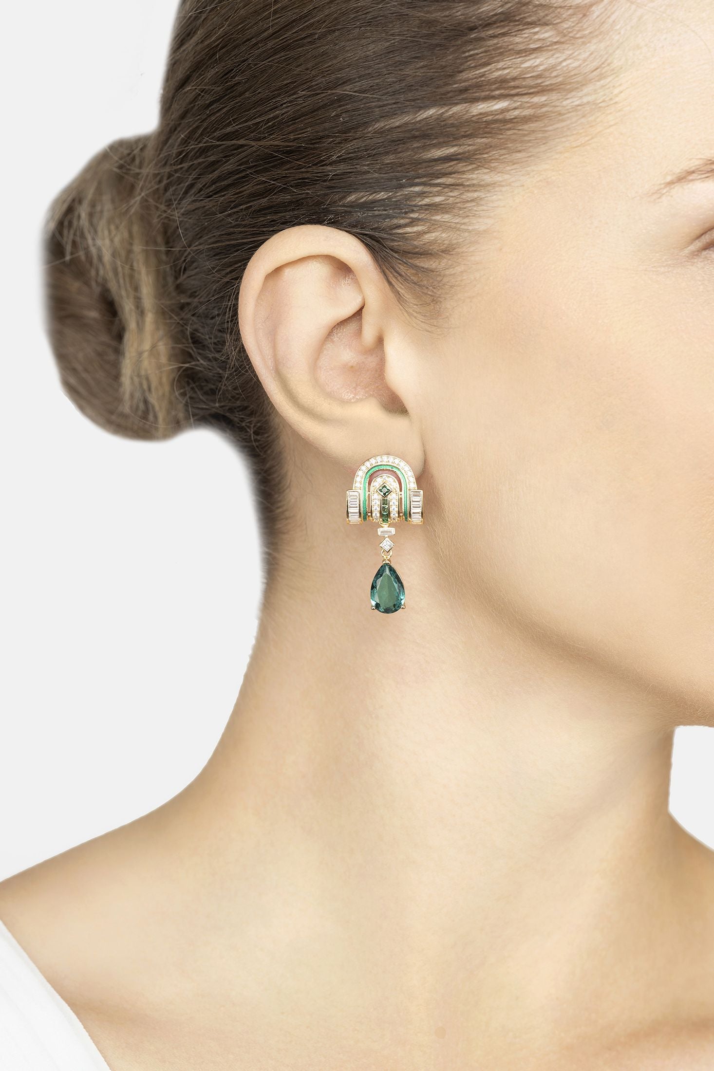 Close-up of a woman wearing a green teardrop earring with a white background