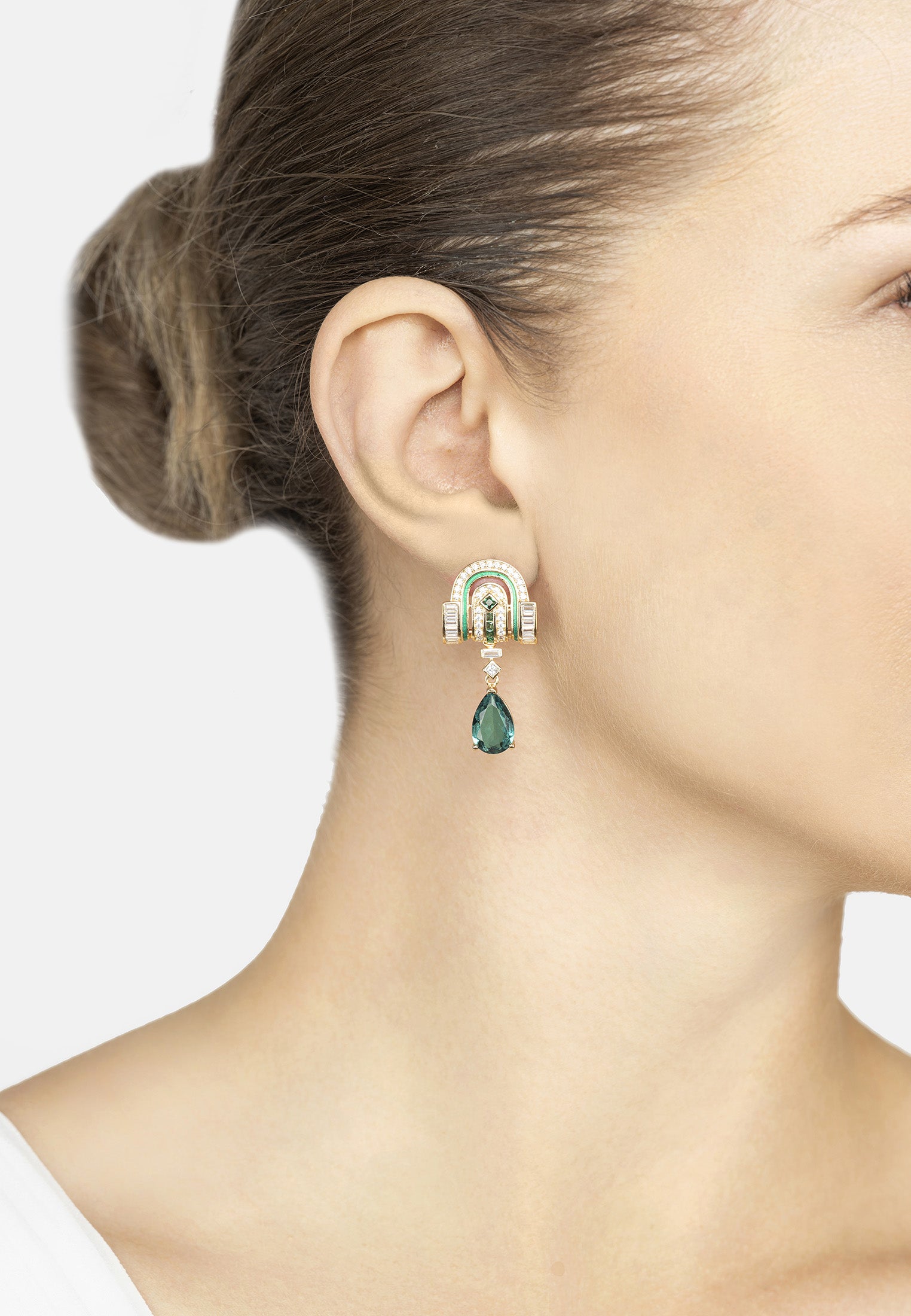 Close-up of a woman wearing a green teardrop earring with a white background