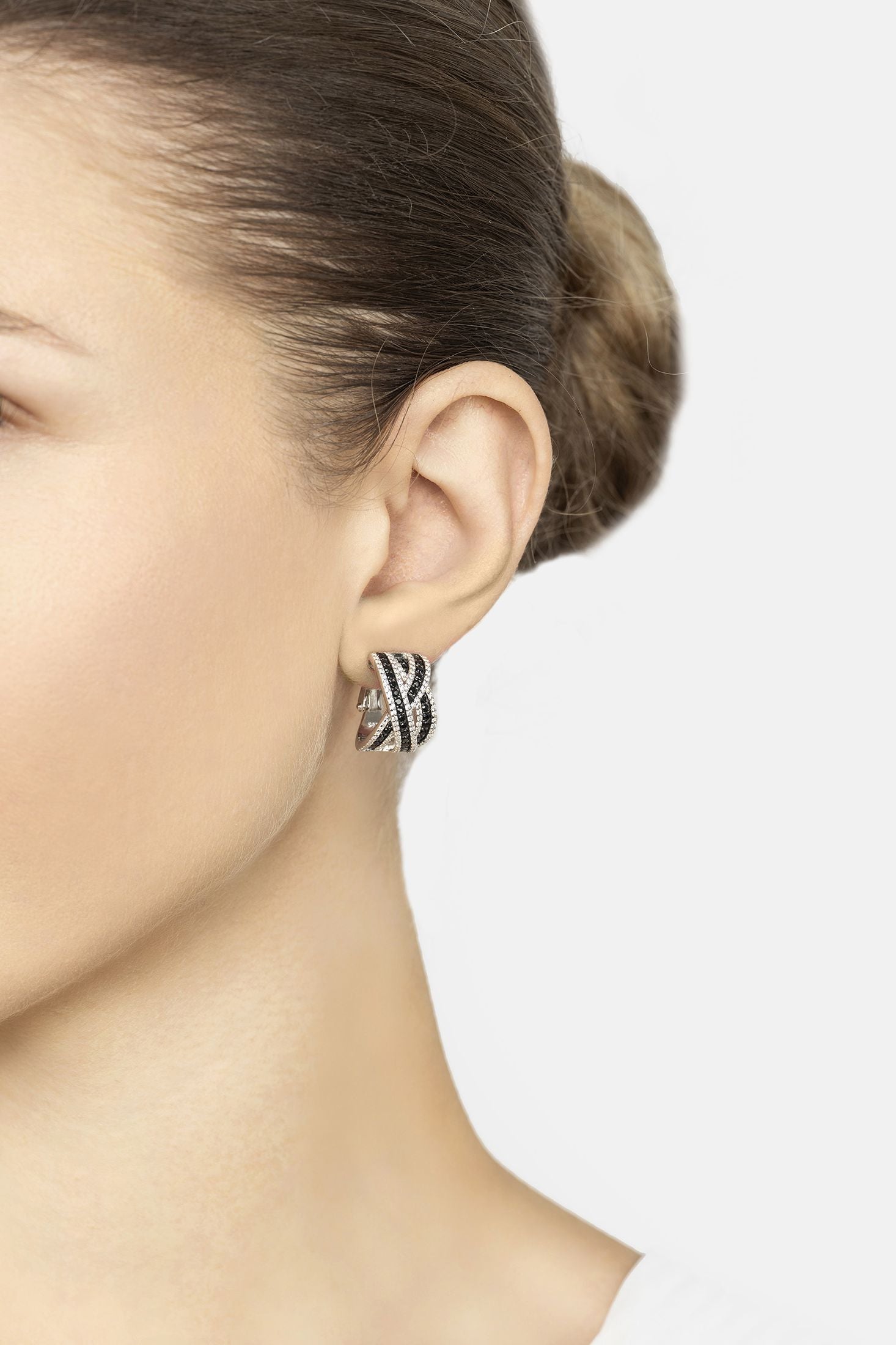 Close-up of a person wearing a blue and gold earring on a plain background