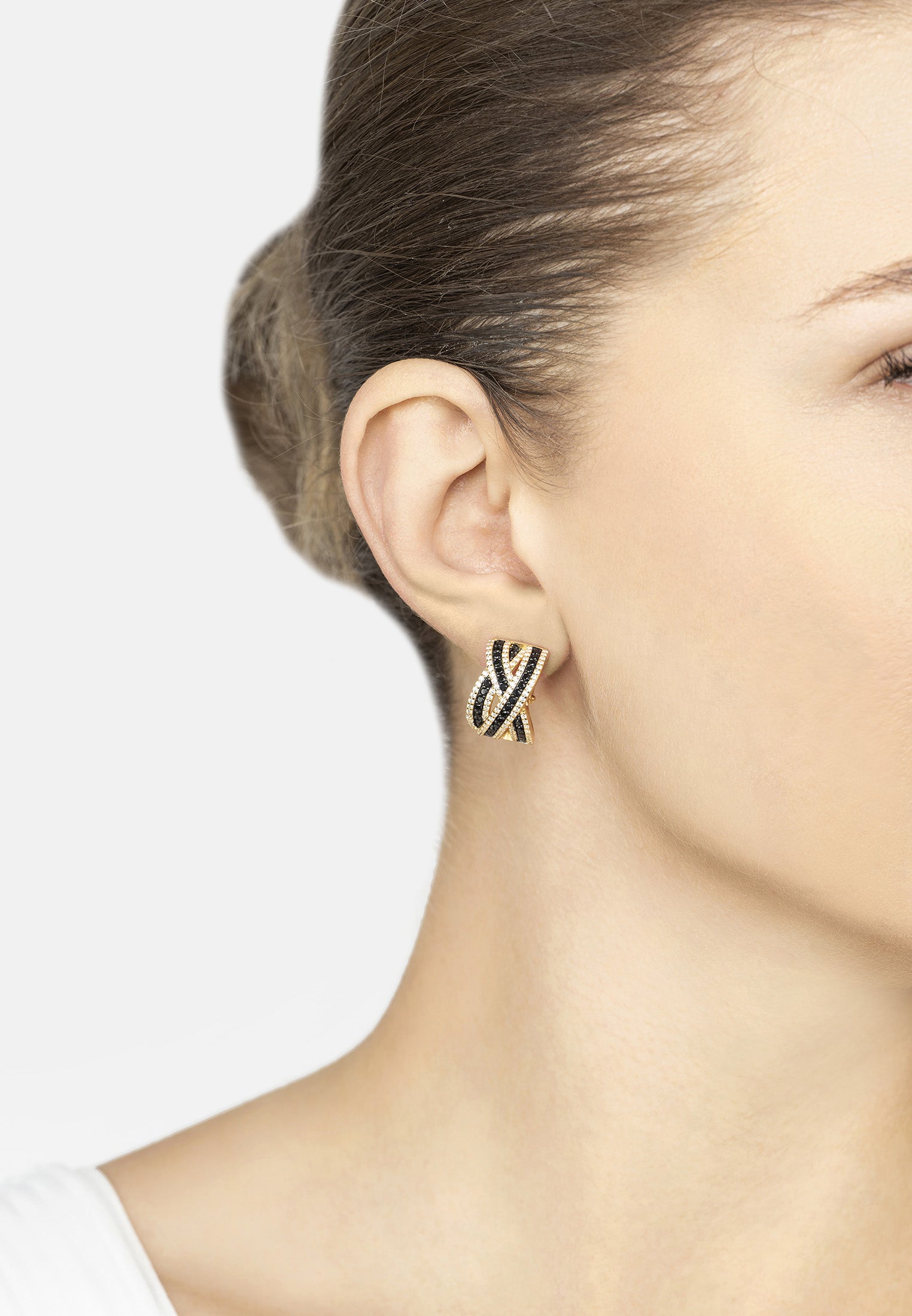 Close-up of a person wearing a gold and black earring on a plain background
