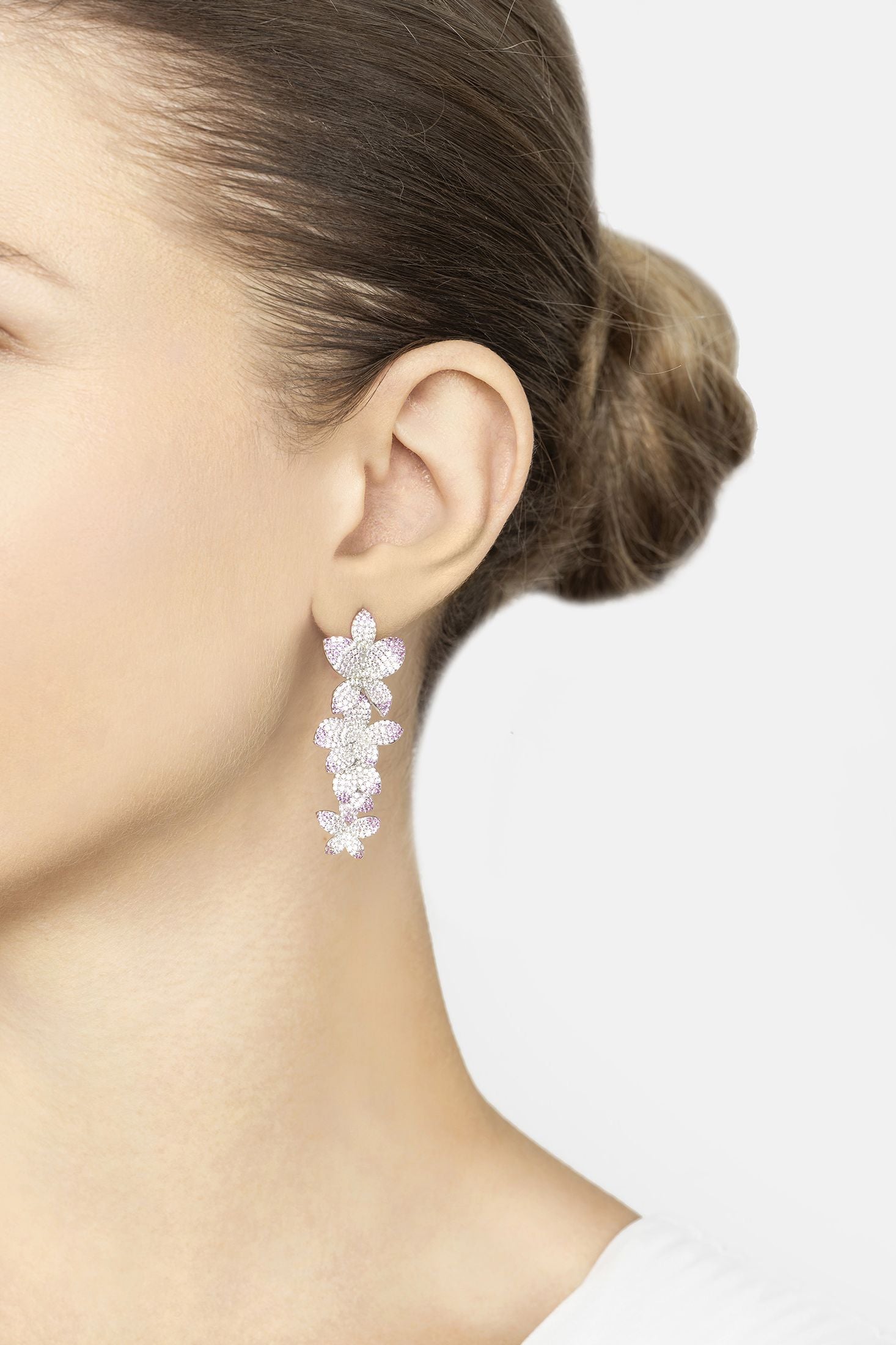 Close-up of a person wearing a floral earring on a plain background