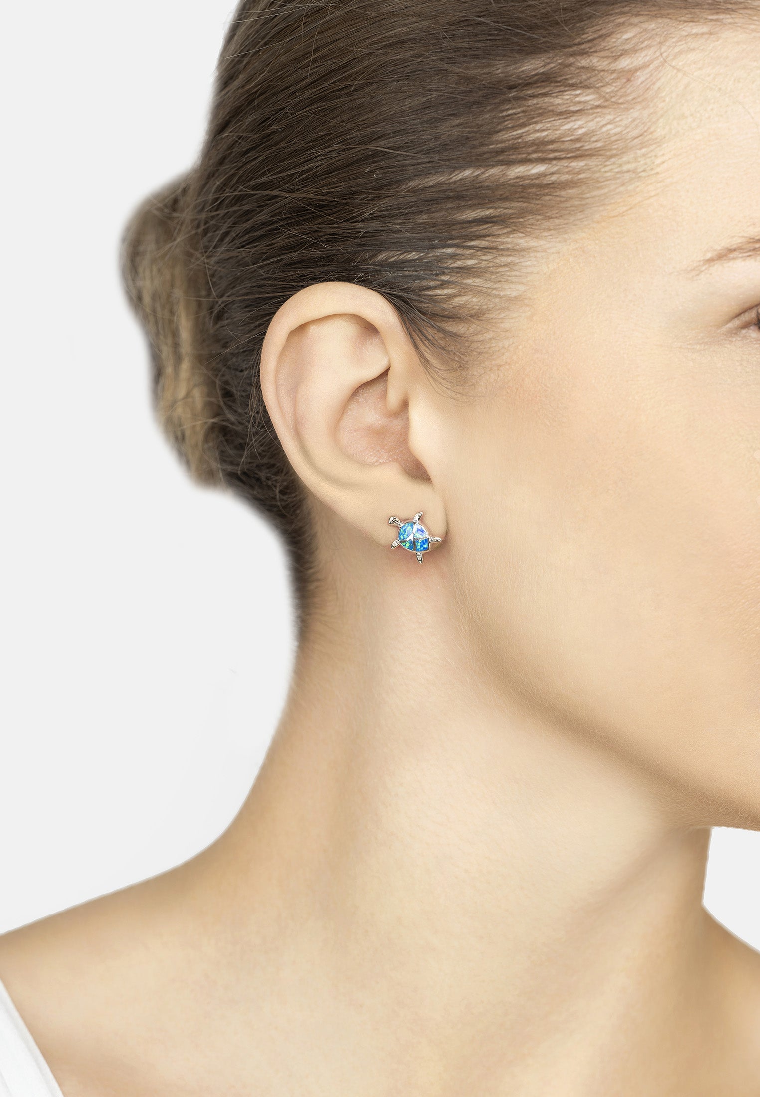 Close-up of a person wearing a blue gemstone earring on a plain background