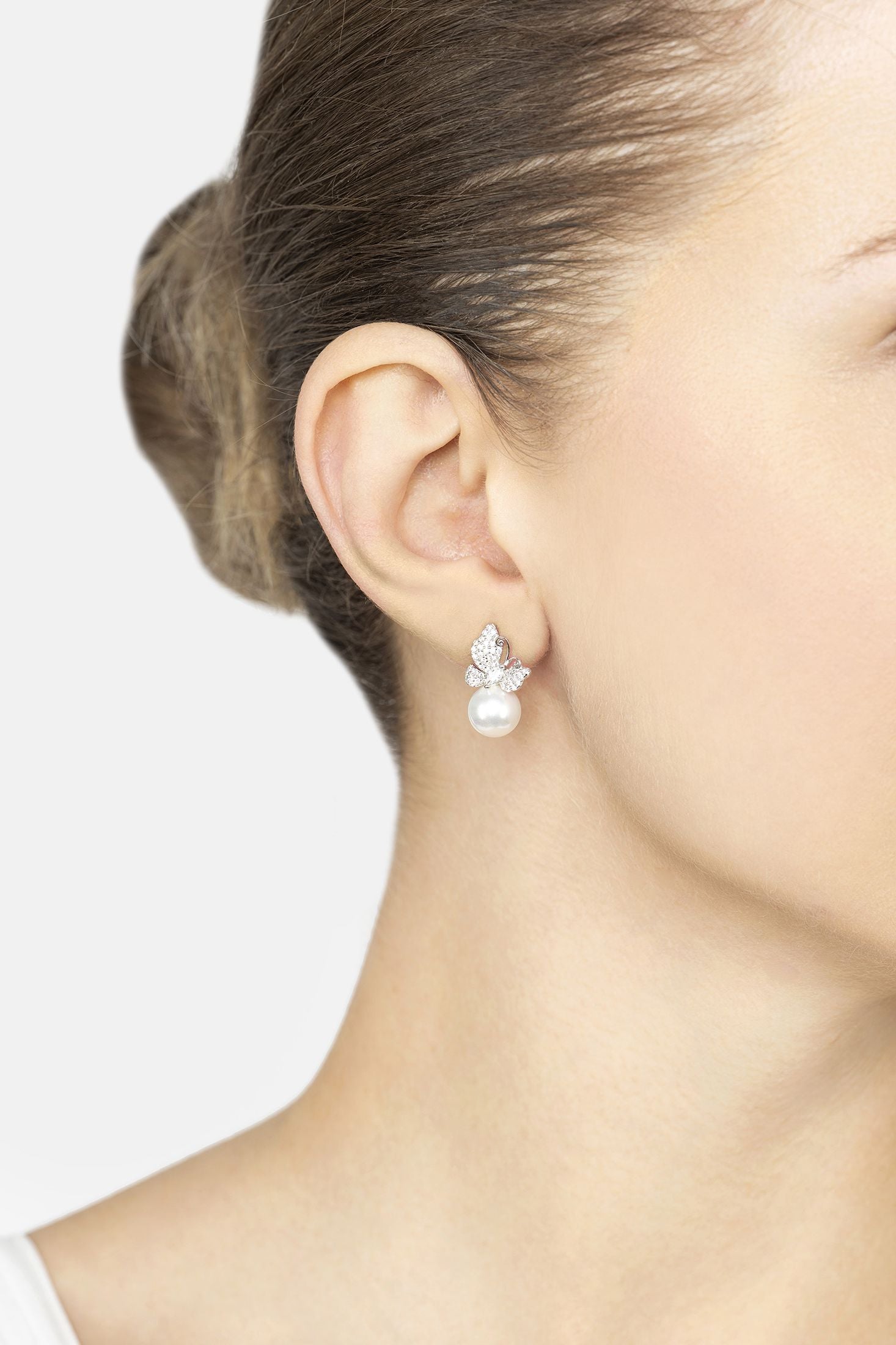Close-up of a person wearing a pearl earring with a white background