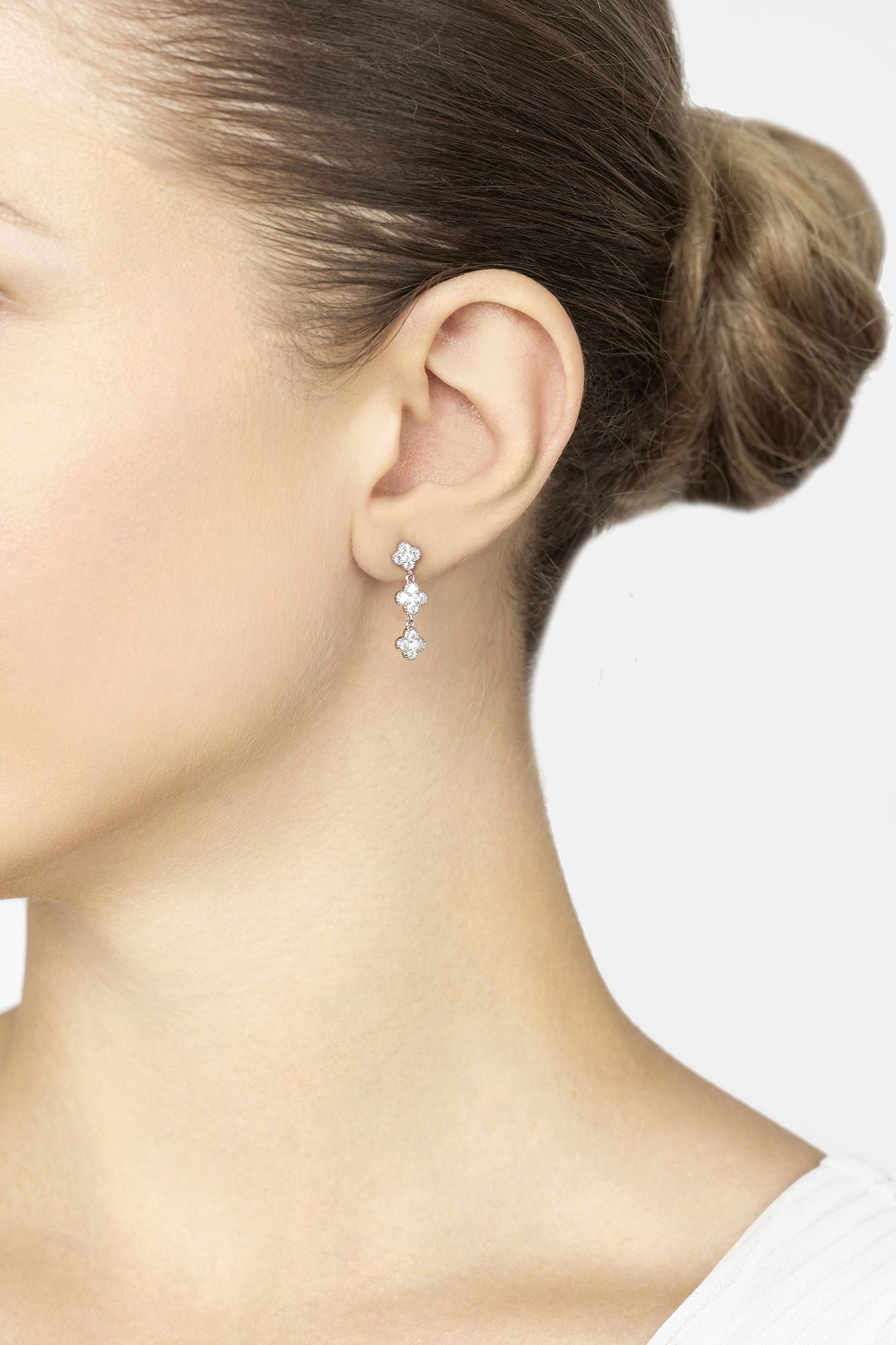 Close-up of a woman wearing a set of earrings with a neutral background
