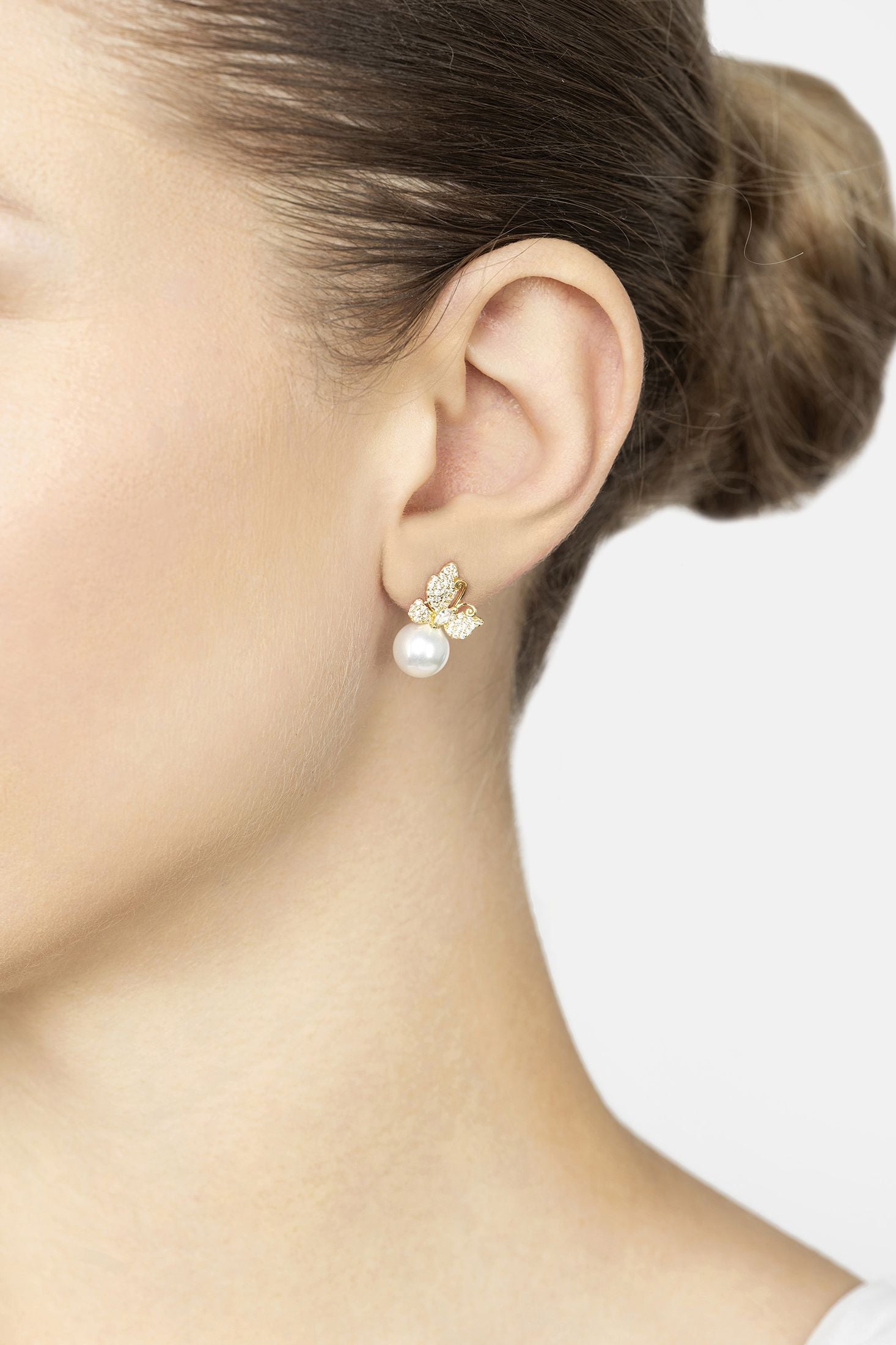 Close-up of an ear wearing a pearl earring with a white background