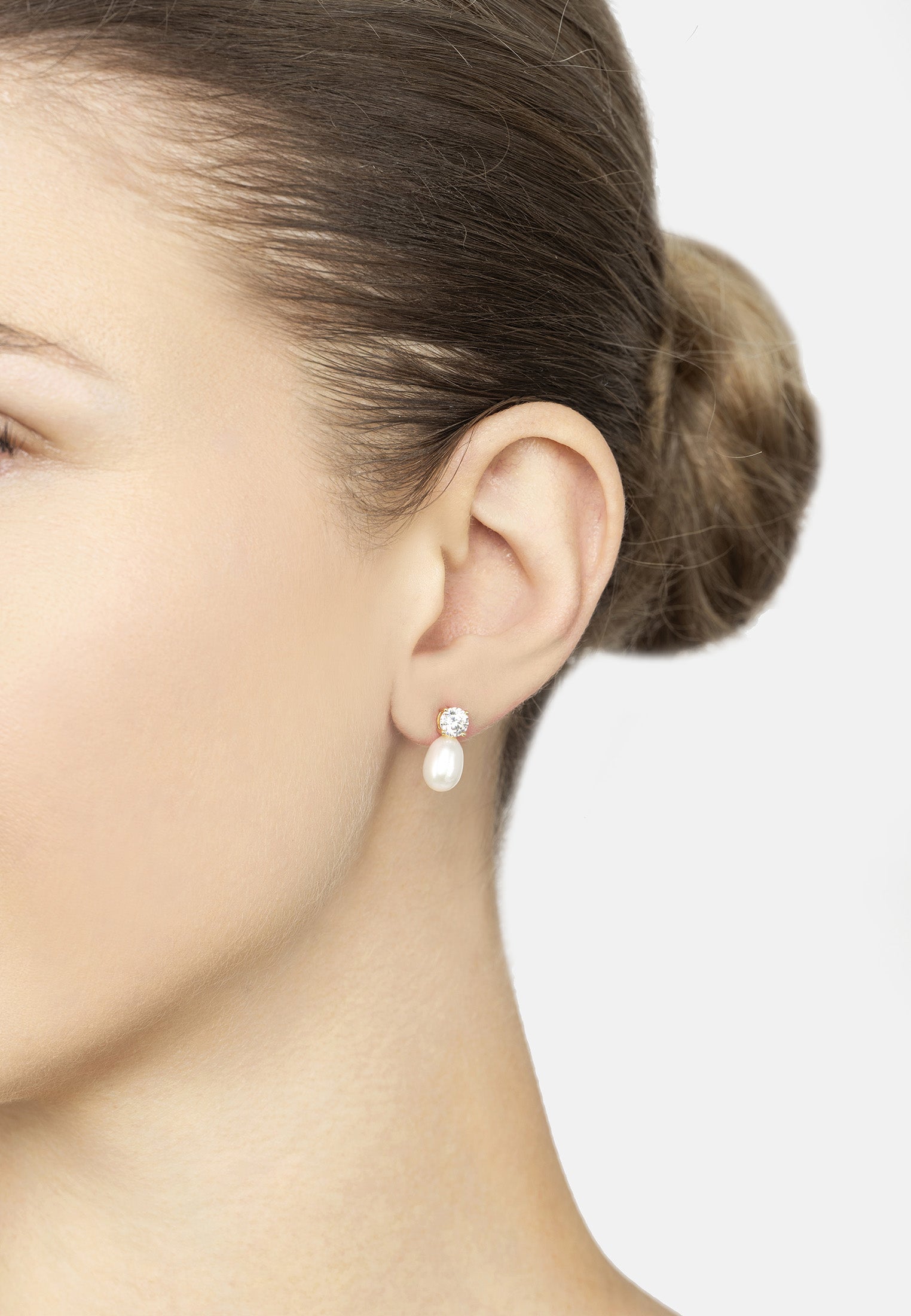 Pearl earring worn by a person on a plain background