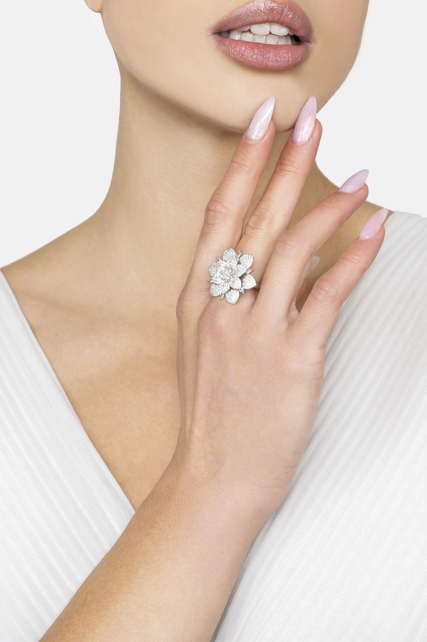 Close-up of a hand wearing a floral silver ring on a white background
